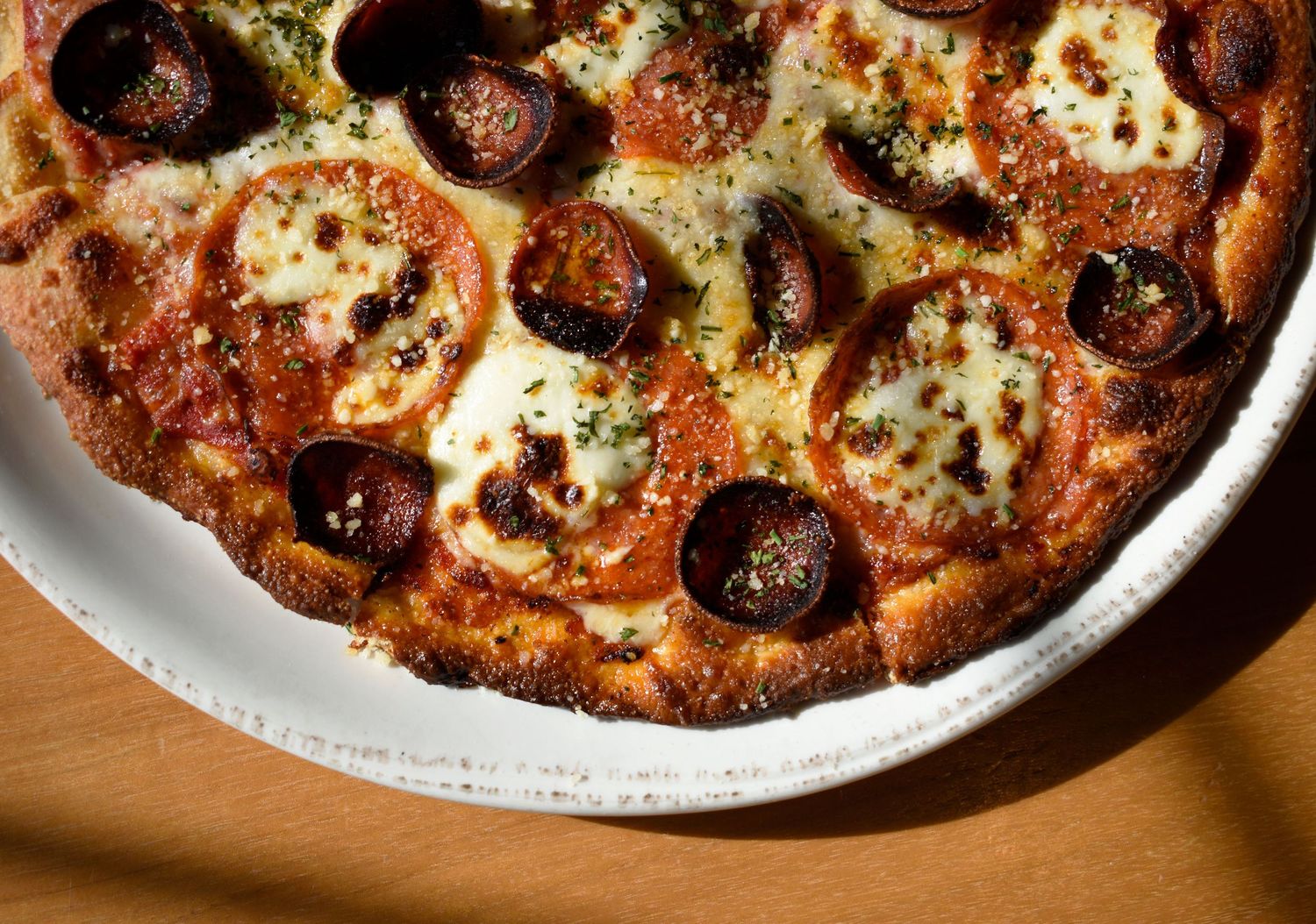 Overhead close-up of a deep dish pepperoni pizza with melted cheese in a white pan.