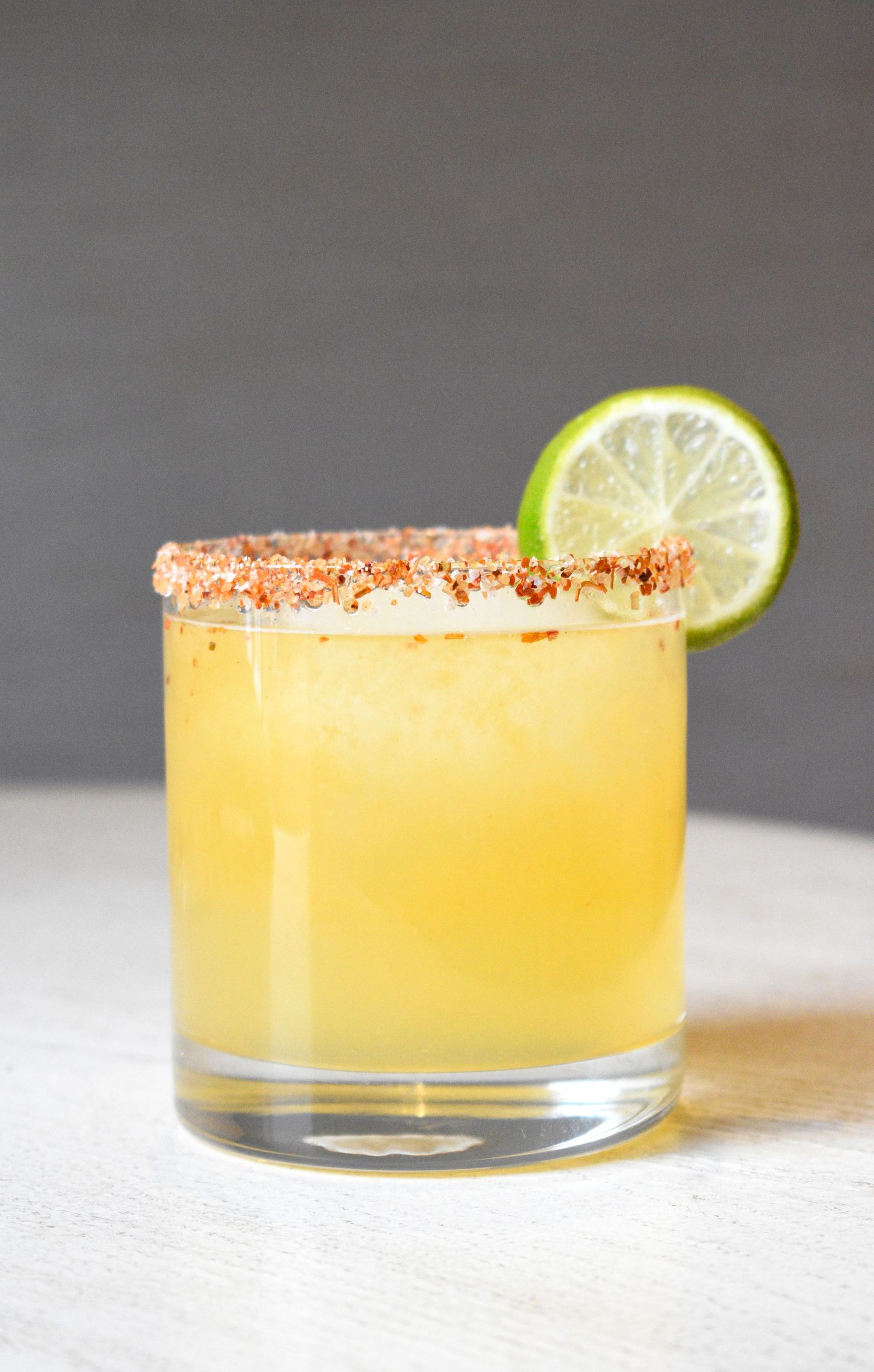 Golden margarita in a rocks glass with spiced chili-salt rim and fresh lime wheel garnish.