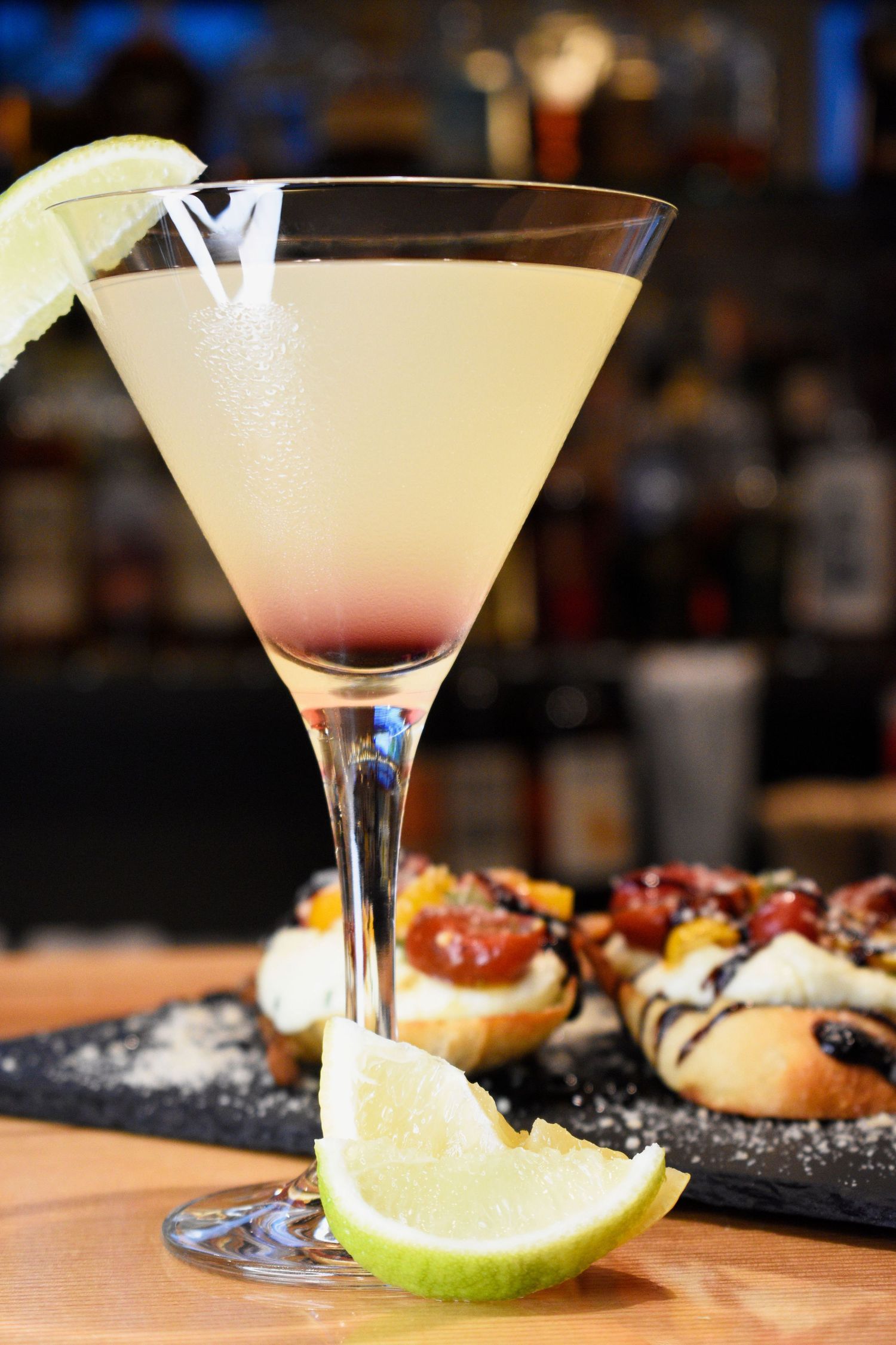 Chilled lime martini cocktail served with bruschetta appetizers at a restaurant bar.