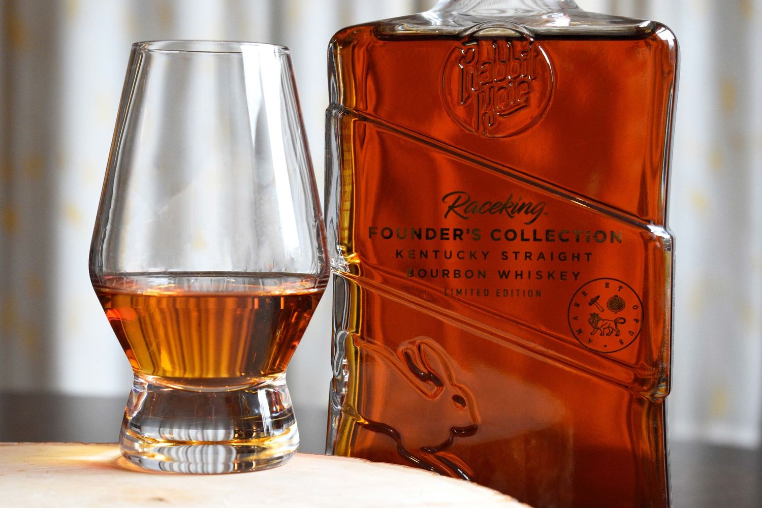 Rousseau Founders Collection Kentucky Straight Bourbon Whiskey decanter with embossed rabbit beside a Glencairn glass.