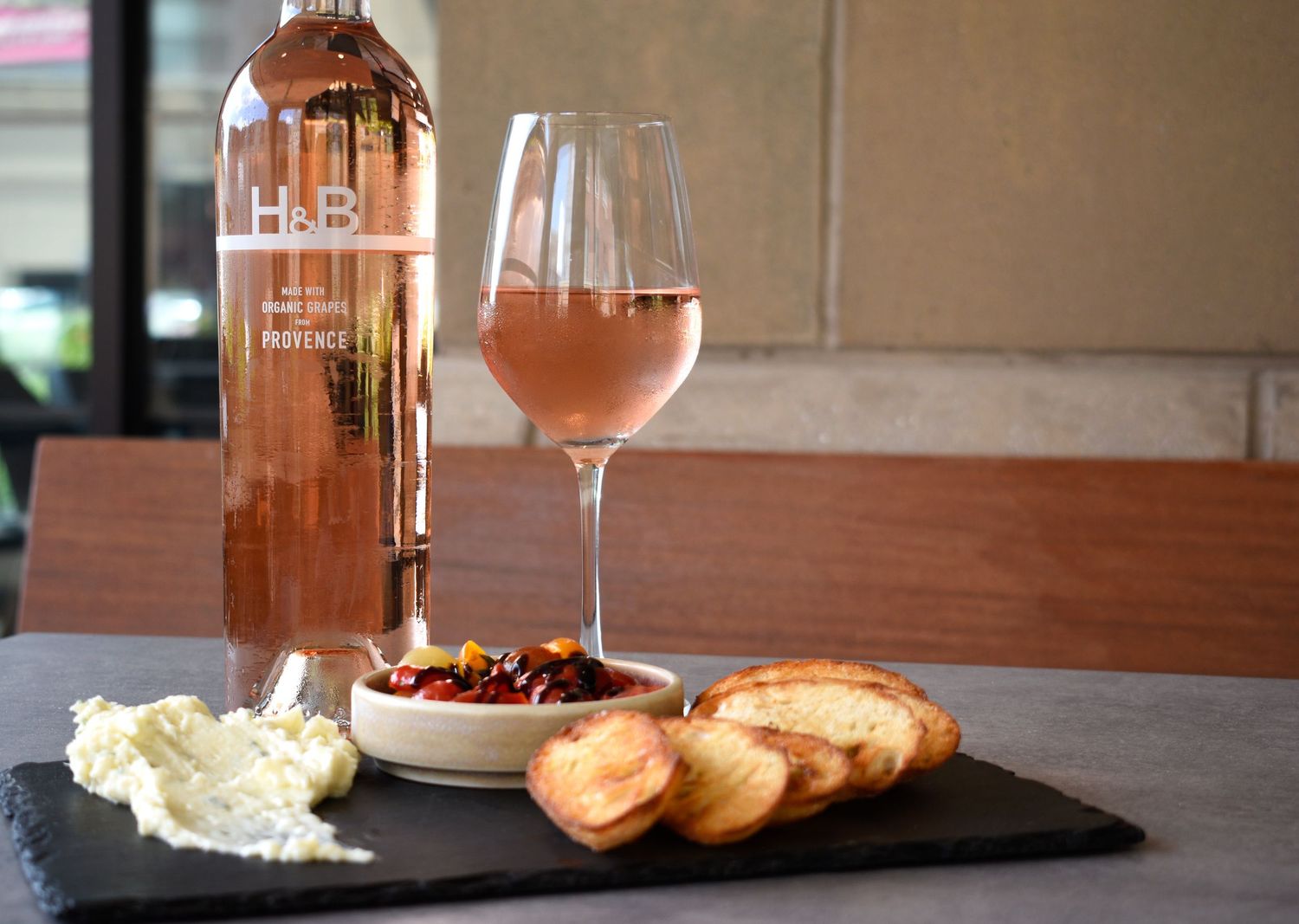 Wine bottle and glass with whipped ricotta, marinated peppers, and toasted crostini on plate. Food & beverage photography in Tampa, FL.