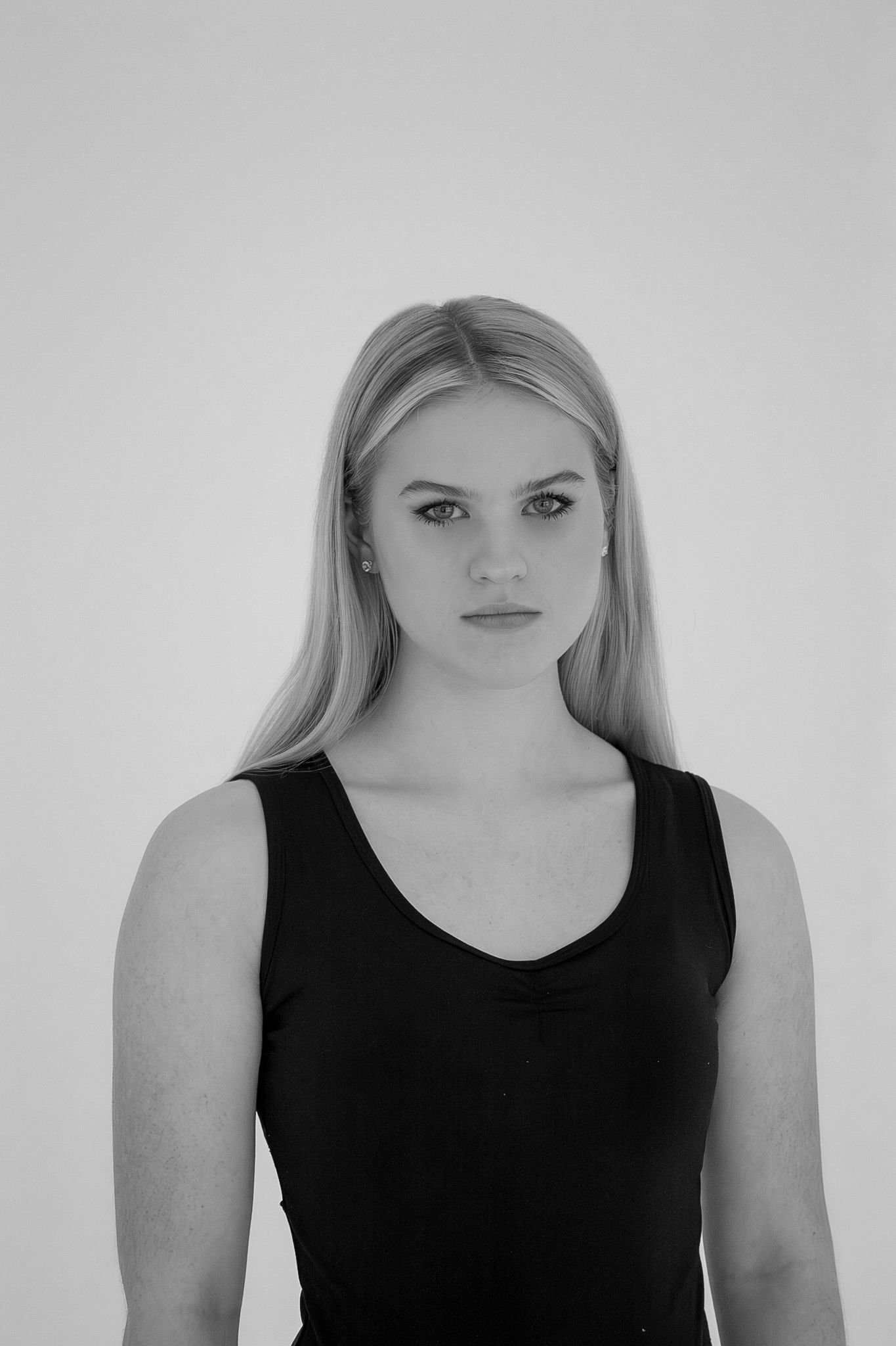 Black and white portrait of blonde woman in black tank top on white background.