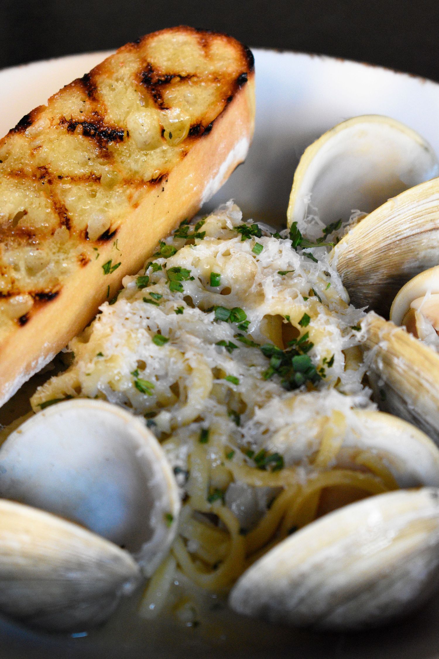 Linguine alle vongole with fresh clams, parmesan, herbs, and grilled garlic bread in a white wine sauce.