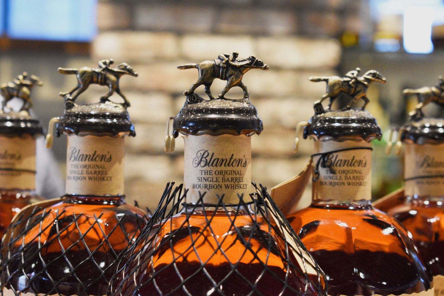 Blanton's Single Barrel bourbon bottles topped with iconic horse and jockey stopper figurines on display.