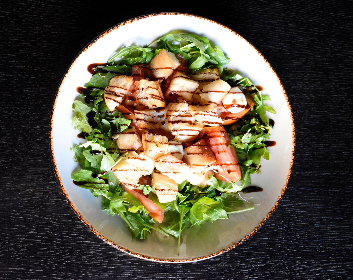 Overhead view of grilled shrimp and scallop salad with arugula and balsamic glaze.