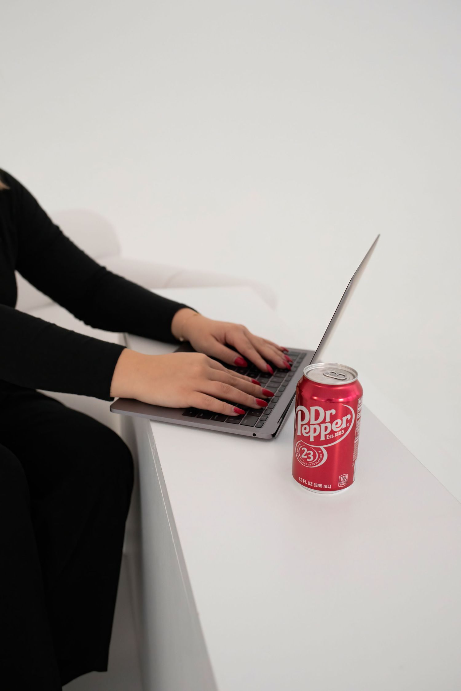 Image of Becka typing on computer with a dr pepper nearby