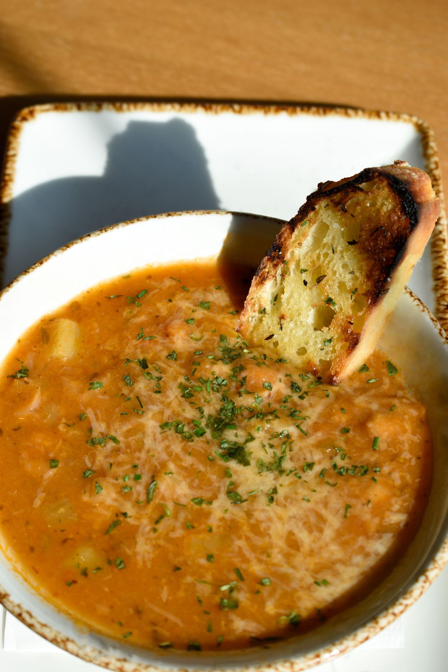 Creamy tomato bisque soup topped with fresh herbs and a toasted bread crouton.