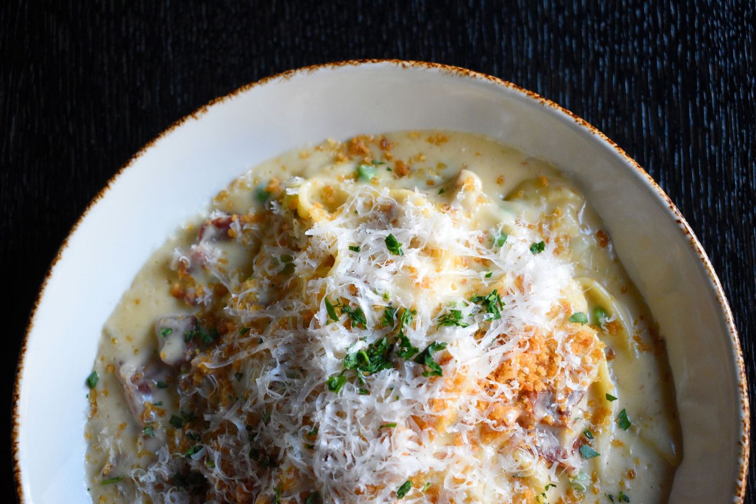 Creamy risotto topped with grated parmesan cheese and fresh herbs served in a wide bowl.