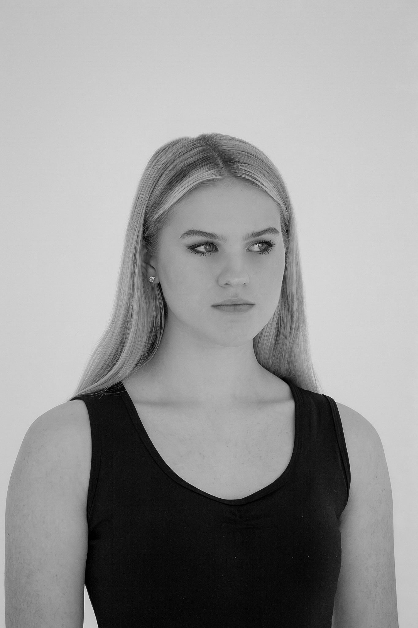 Black and white portrait of blonde woman in black tank top on white background.