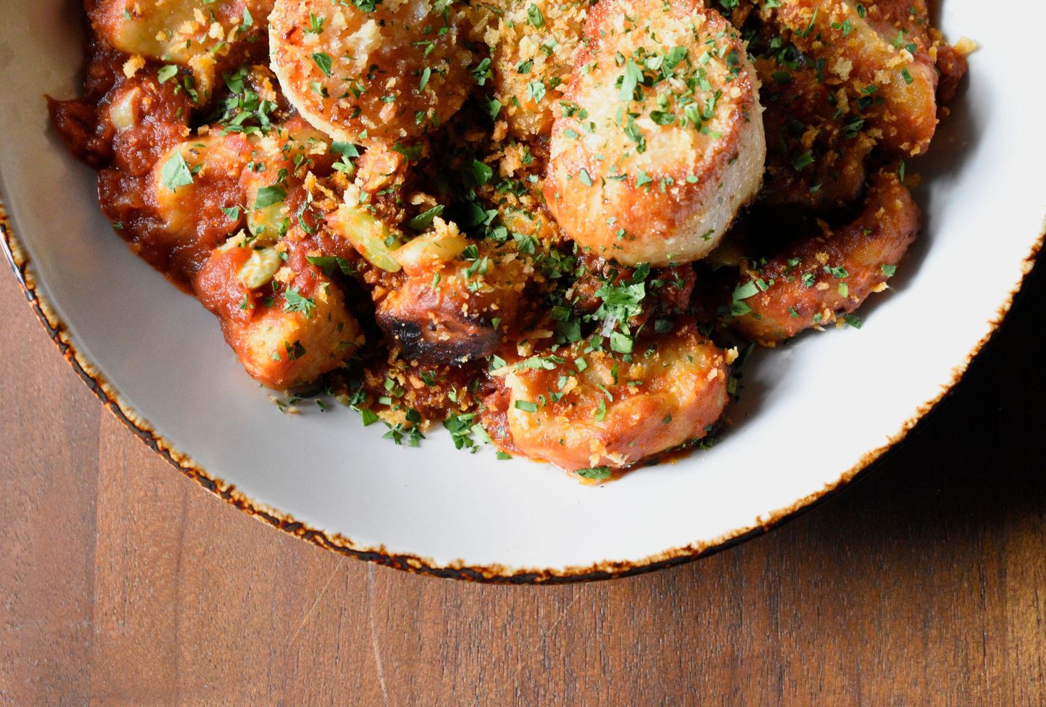 Close-up of Italian polpette meatballs in rich tomato sauce topped with herbs and breadcrumbs.