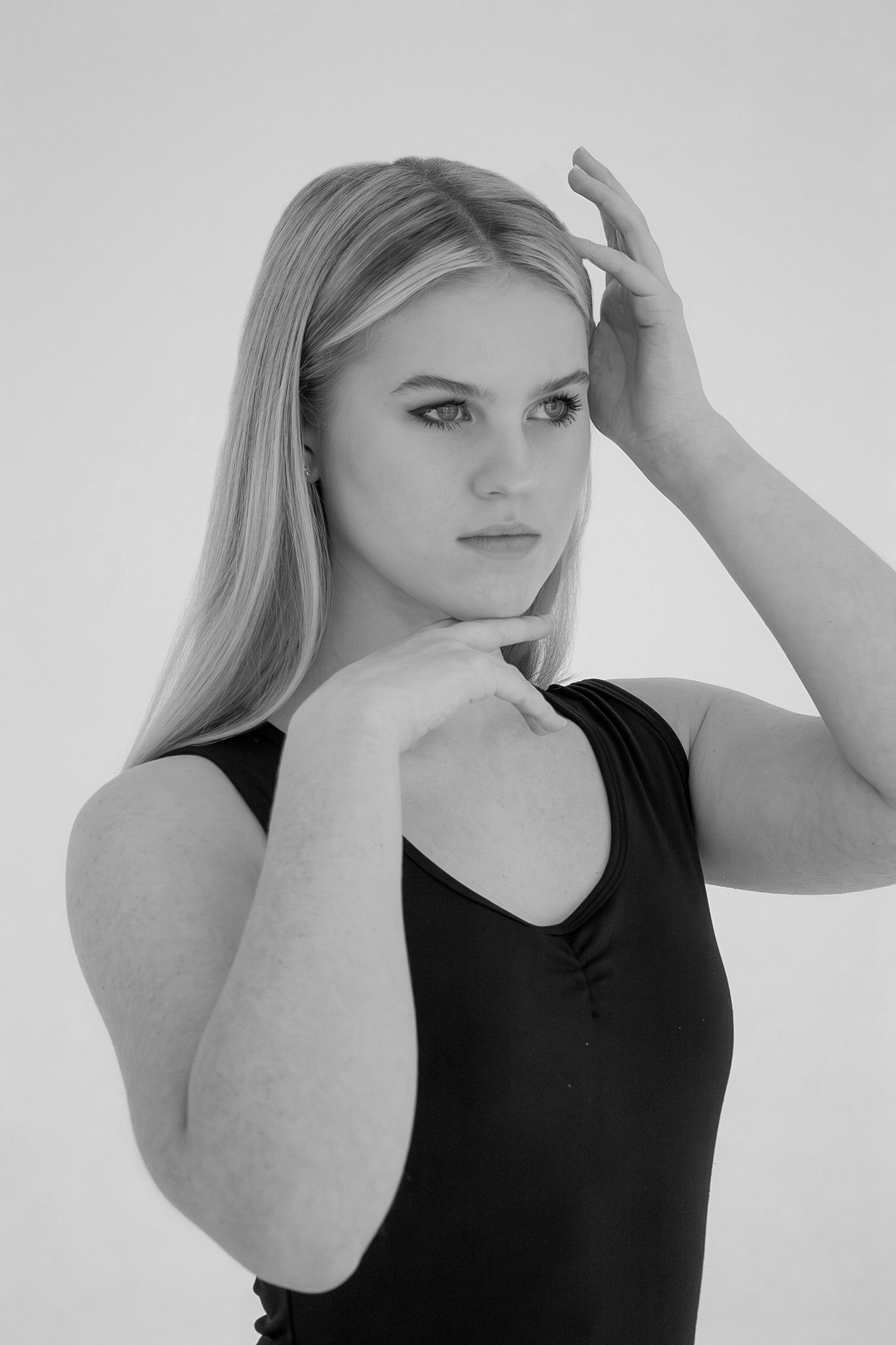 Black and white portrait of blonde woman in black top posing gracefully.
