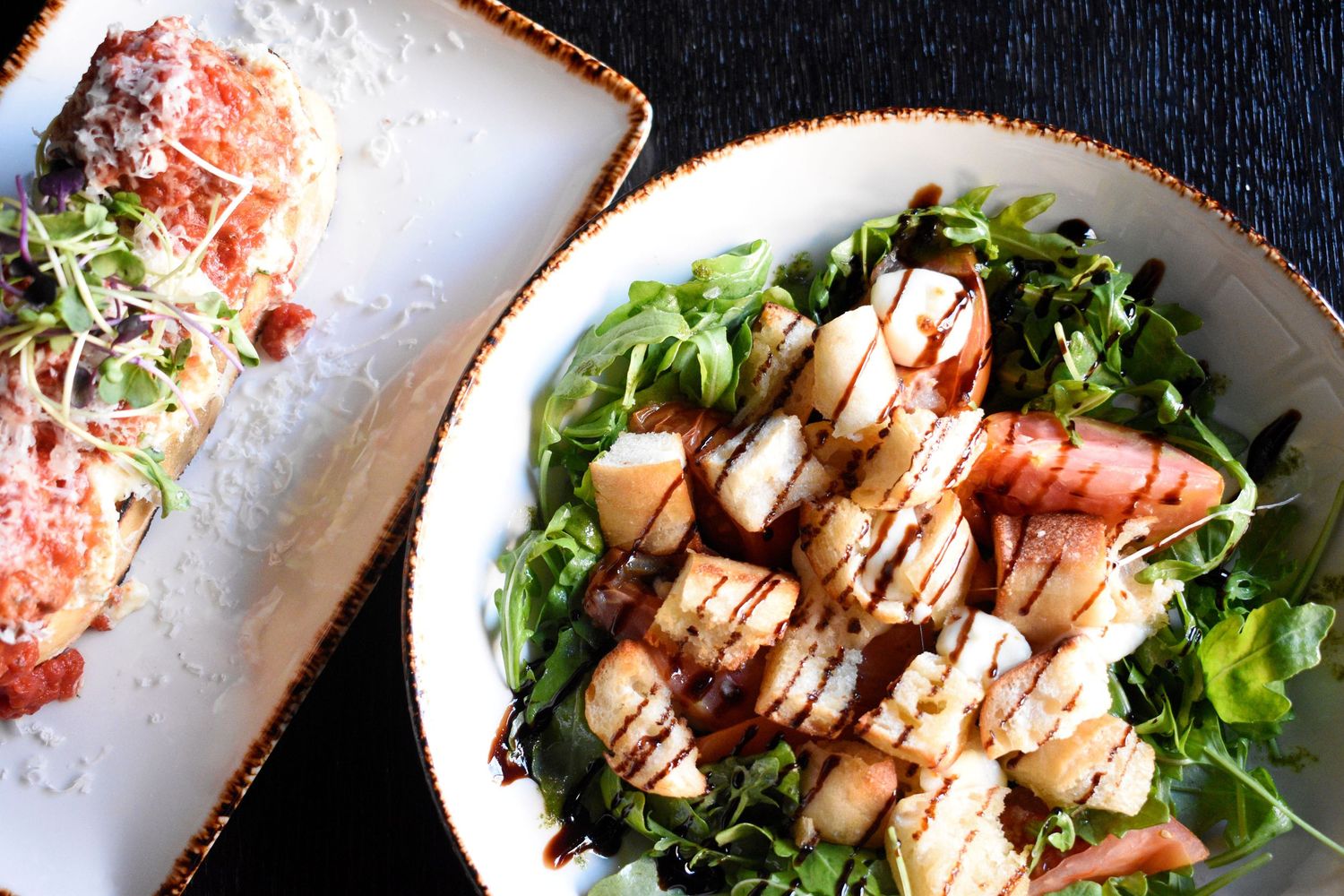 A gourmet scallop salad with arugula and balsamic glaze served in a white bowl.