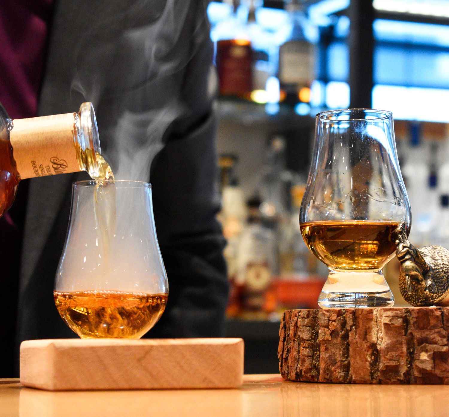 Bartender pouring steaming whisky into a glass during a whisky tasting experience.