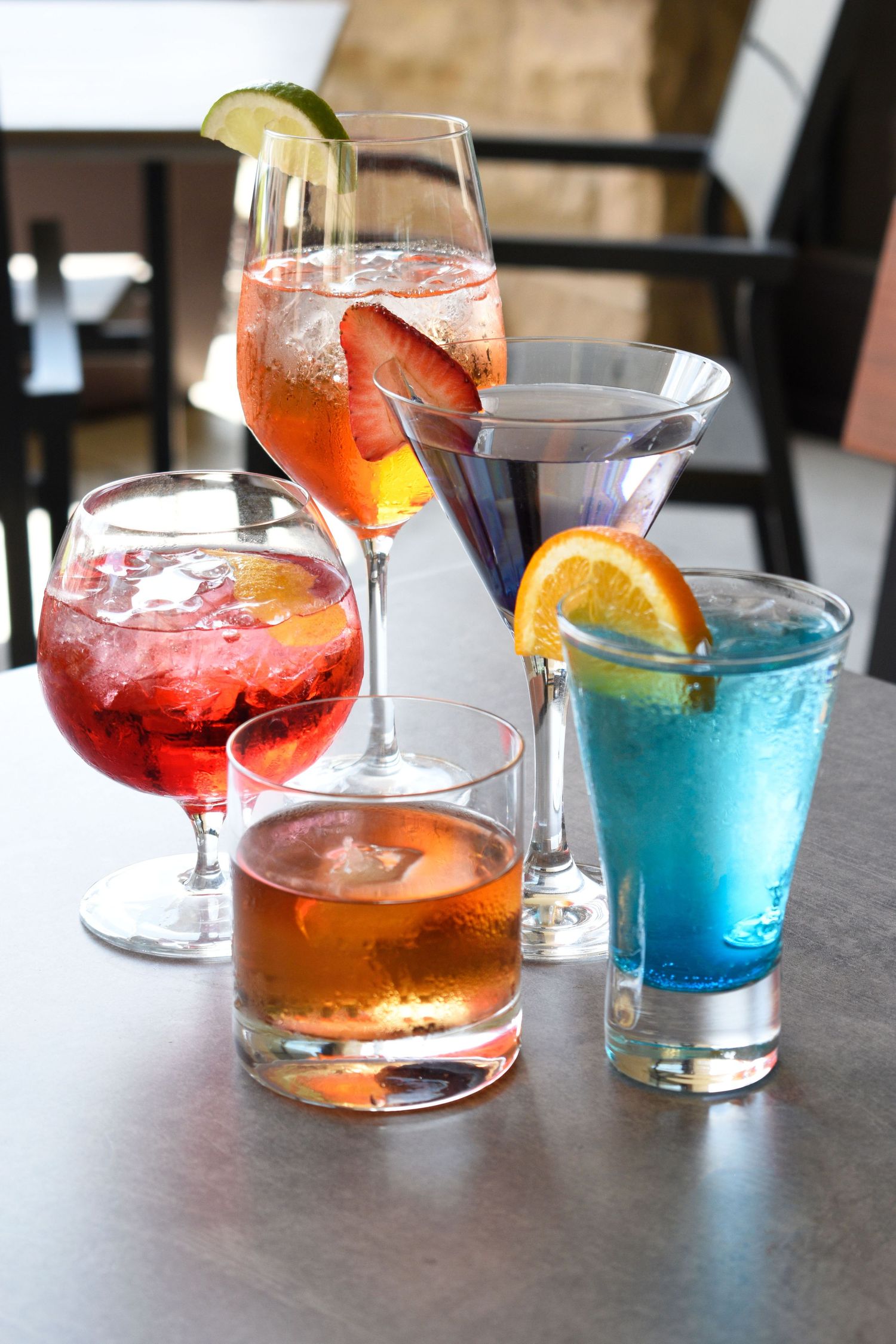 Colorful assortment of cocktails with fruit garnishes on a restaurant table.