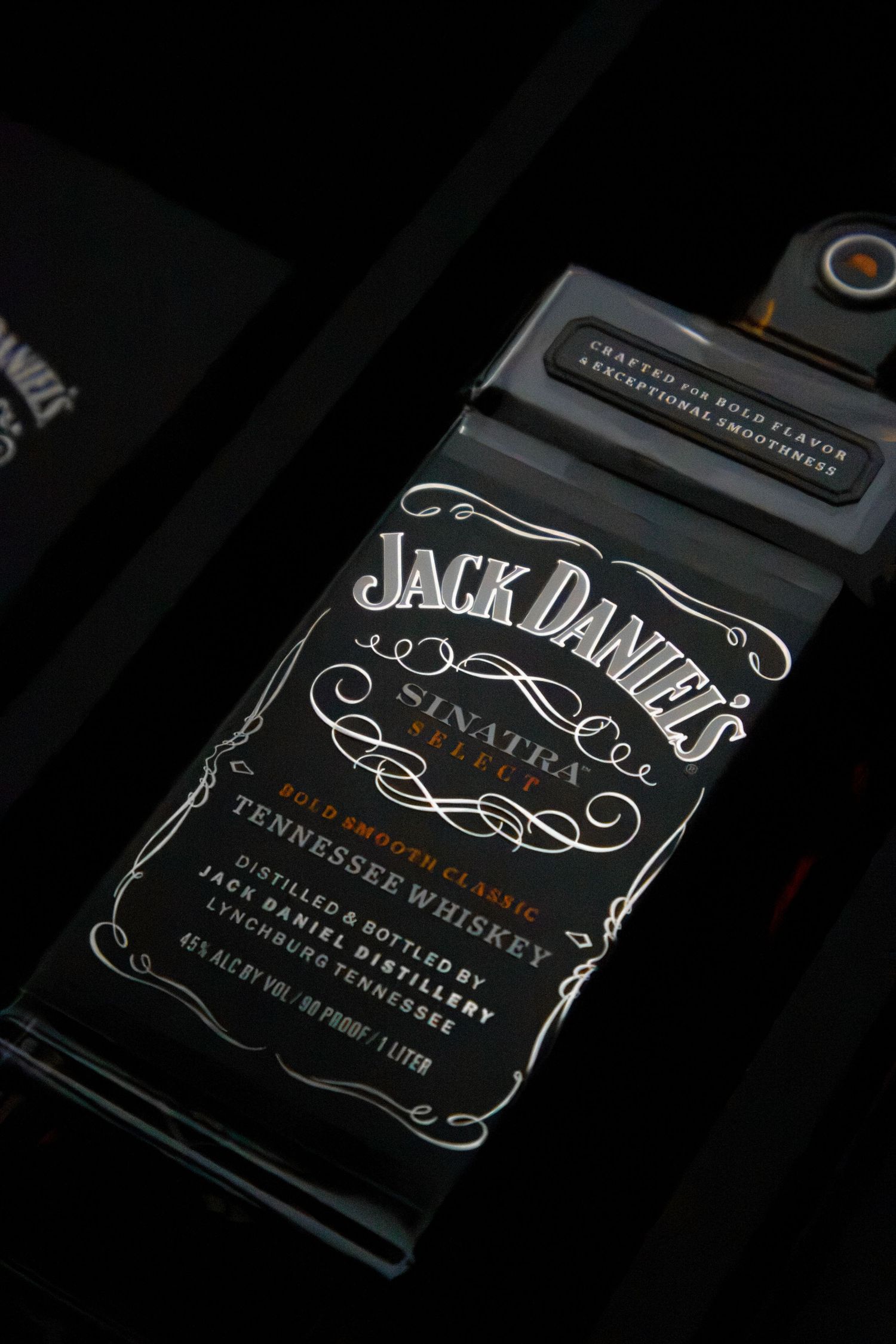Close-up of Jack Daniel's Sinatra Select Tennessee Whiskey bottle label with elegant silver design on black background.