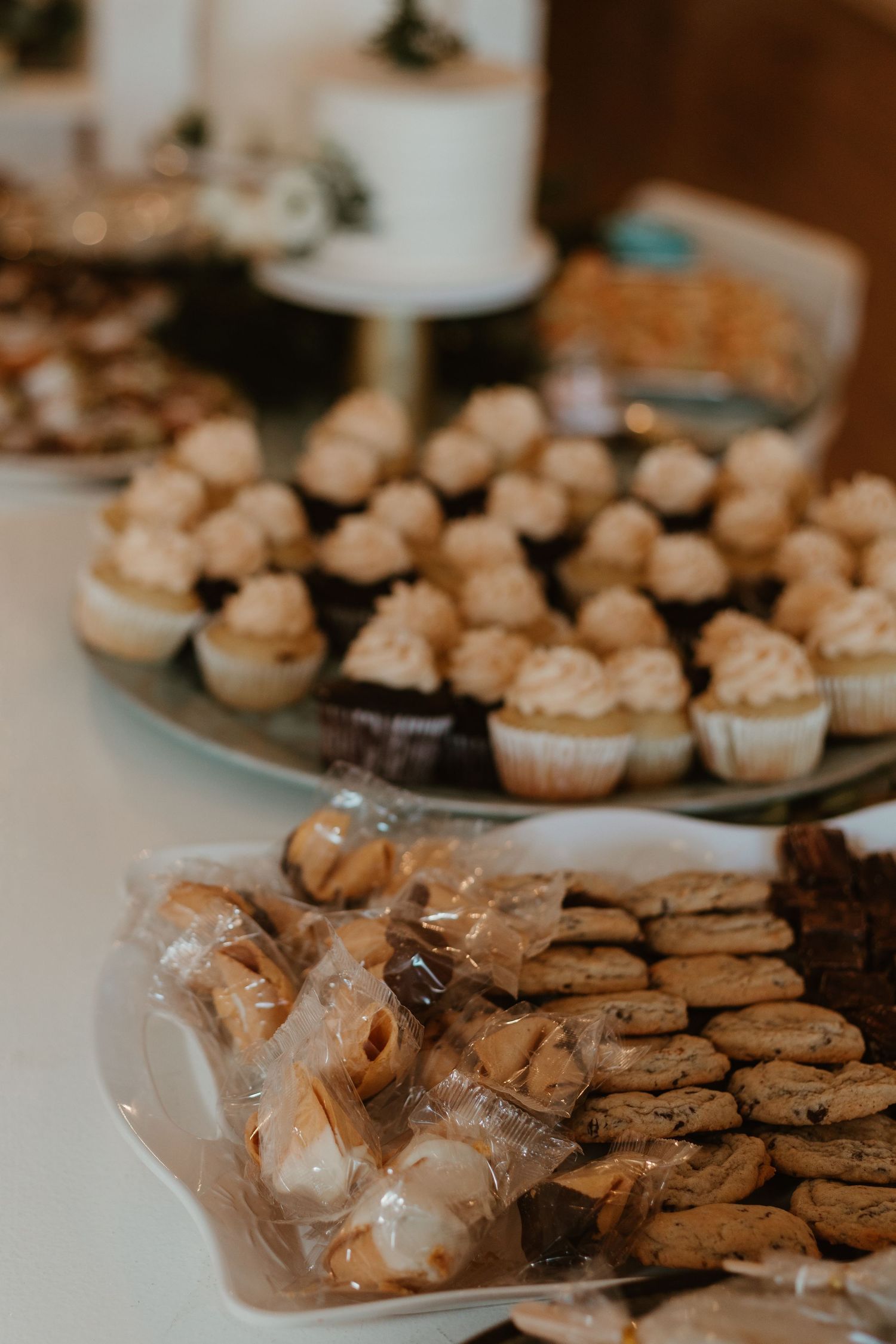 Dessert table with cupcakes, cookies, and s'mores treats at a wedding reception.