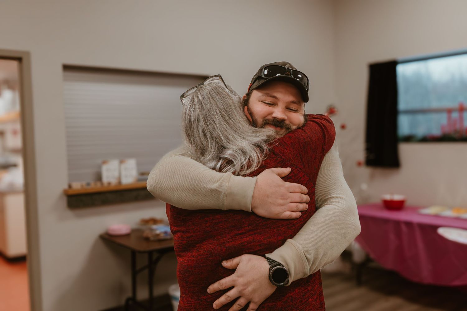 Two people sharing a warm hug in a cozy indoor setting, expressing joy and connection.