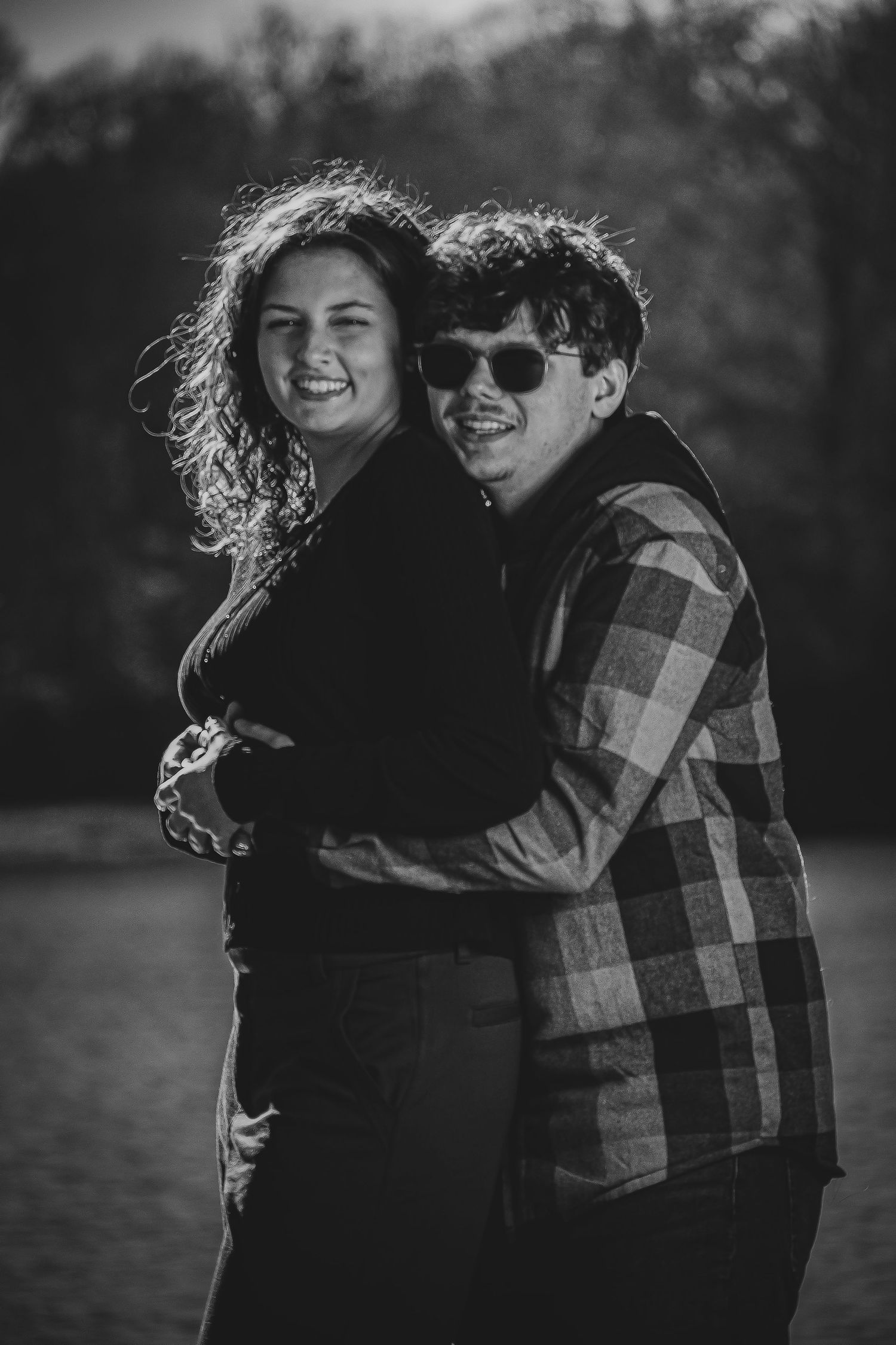 A couple embraces and laughs together in a series of black and white romantic outdoor portraits.