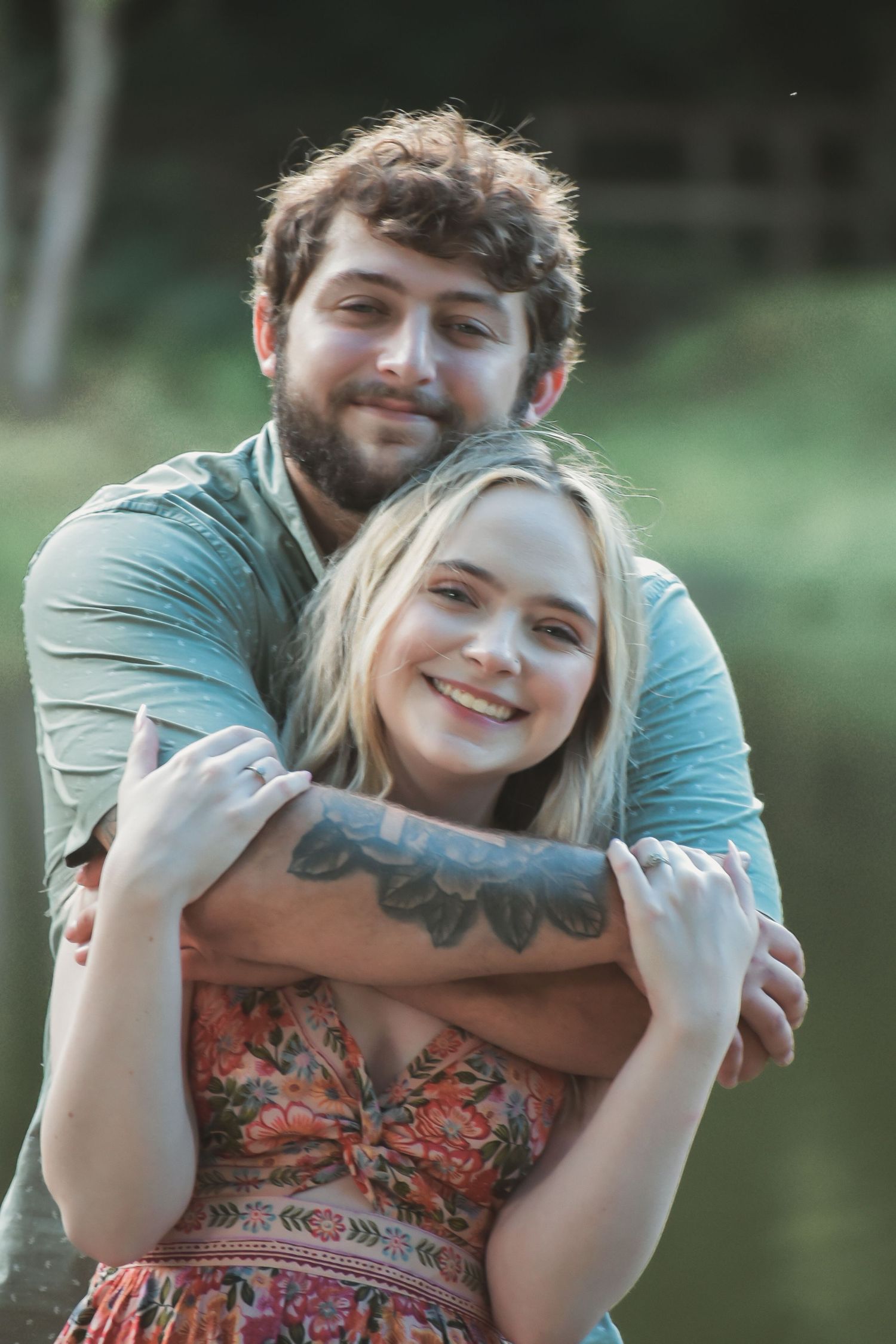 A playful outdoor photoshoot showing a couple's affectionate interaction by a lake.