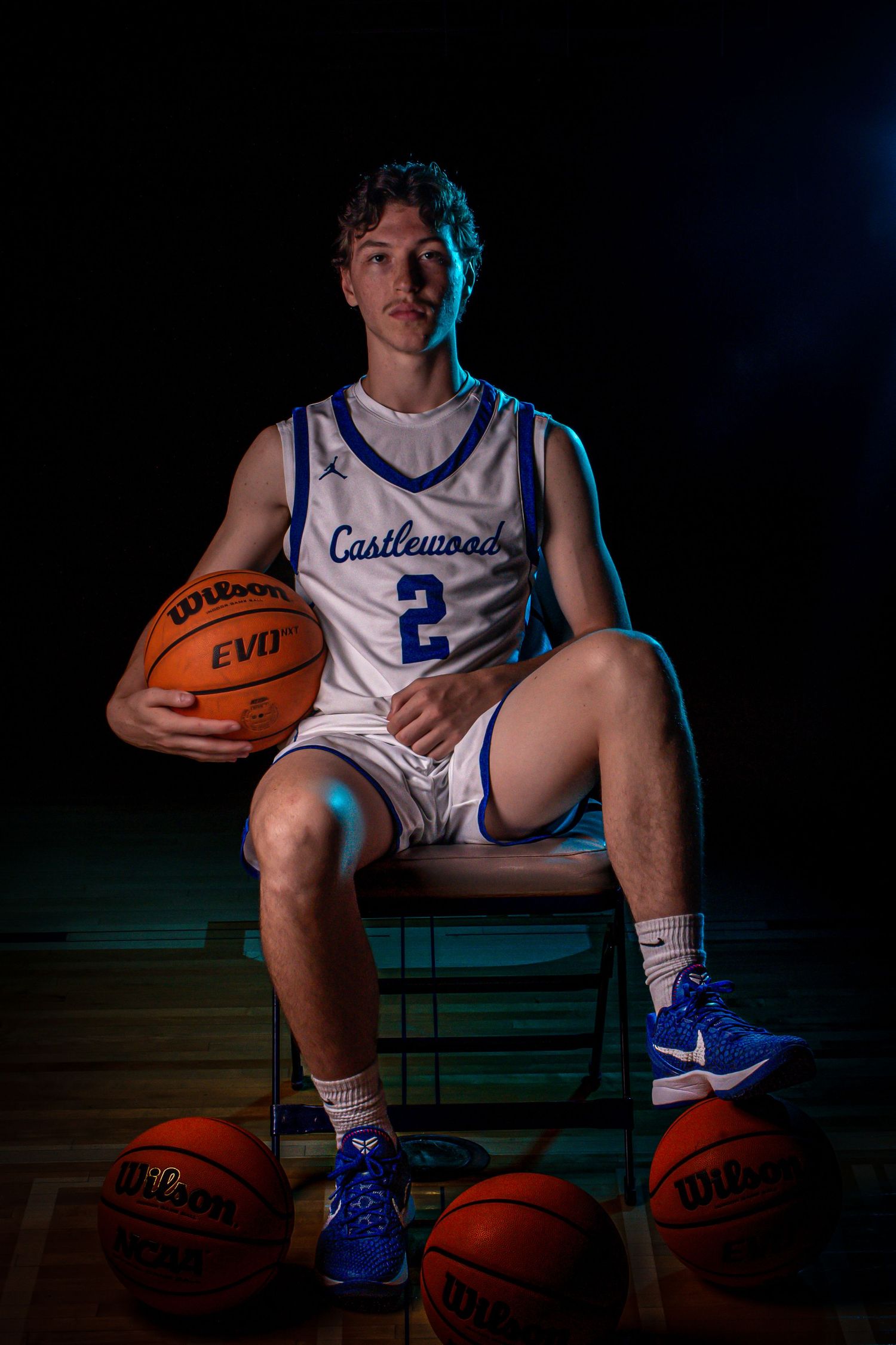 Basketball player in Castlewood jersey number 2 poses with multiple basketballs in studio setting.