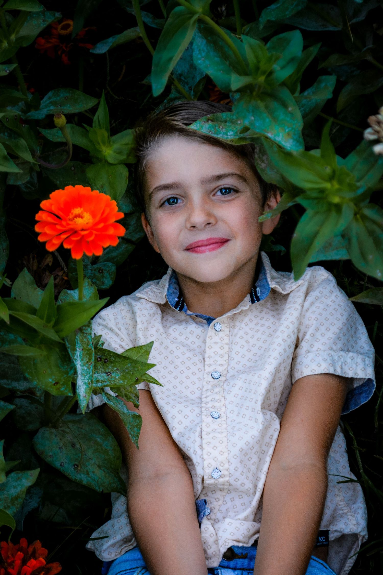 Colorful orange zinnias surround a garden portrait scene.
