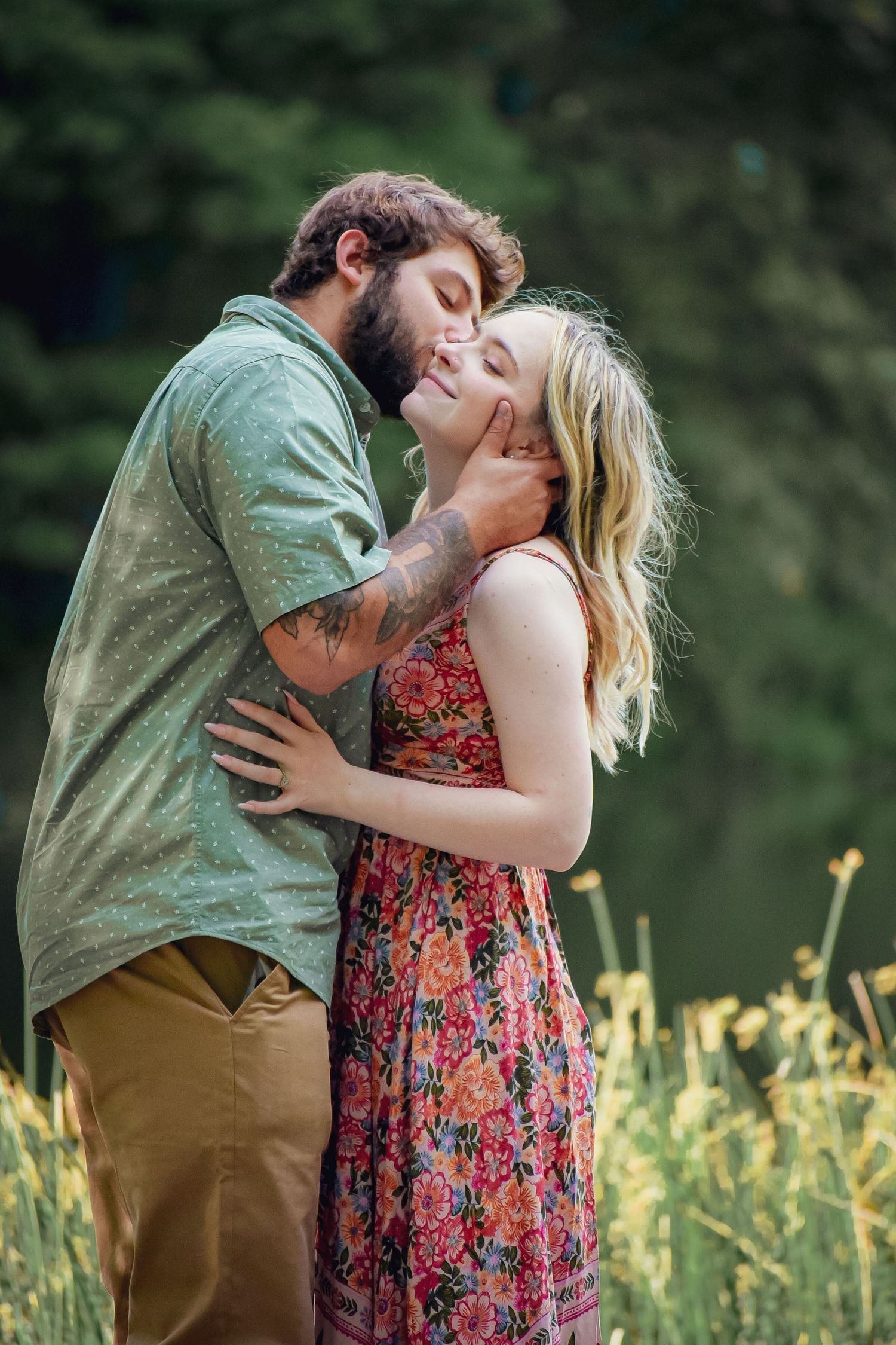 A romantic embrace captured in a natural setting with yellow wildflowers and a lake.