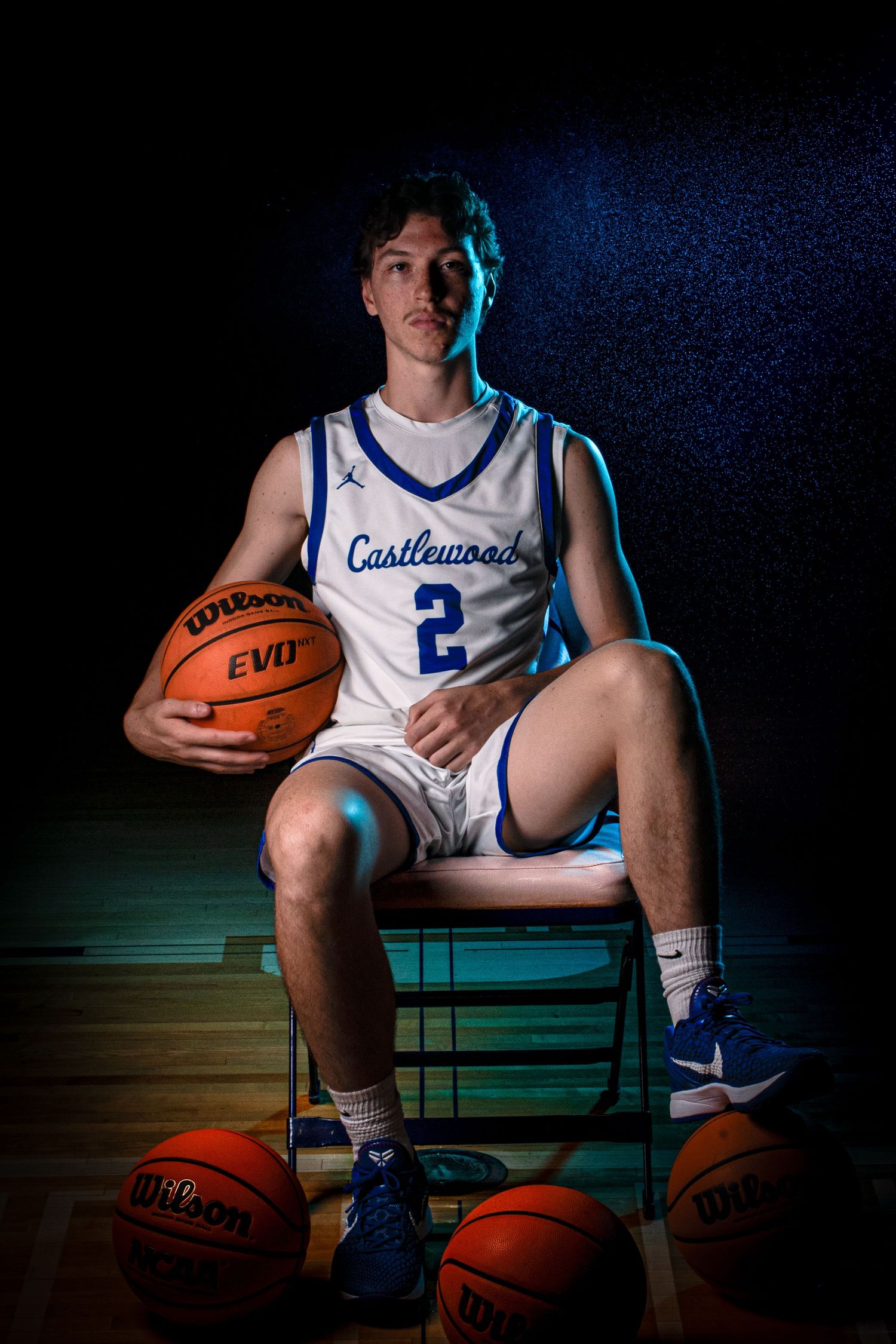 Player in Castlewood jersey number 2 poses with basketballs in moody studio lighting.