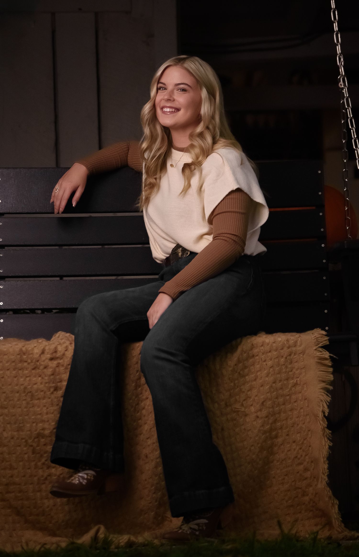 Casual portrait on rustic wooden bench with cozy brown cushions and industrial chain decor.