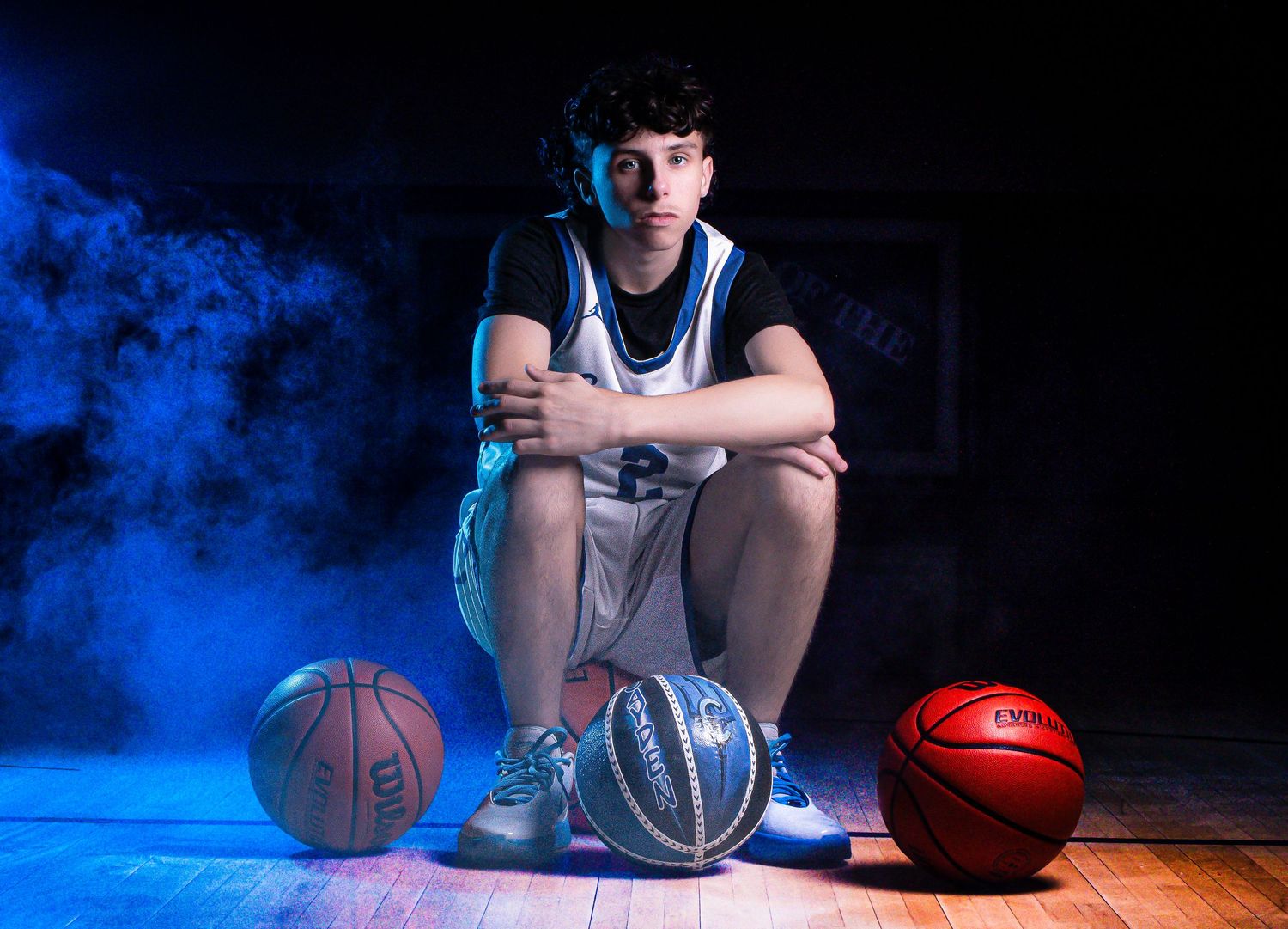 Basketball player with multiple balls on court floor with blue smoke effects.
