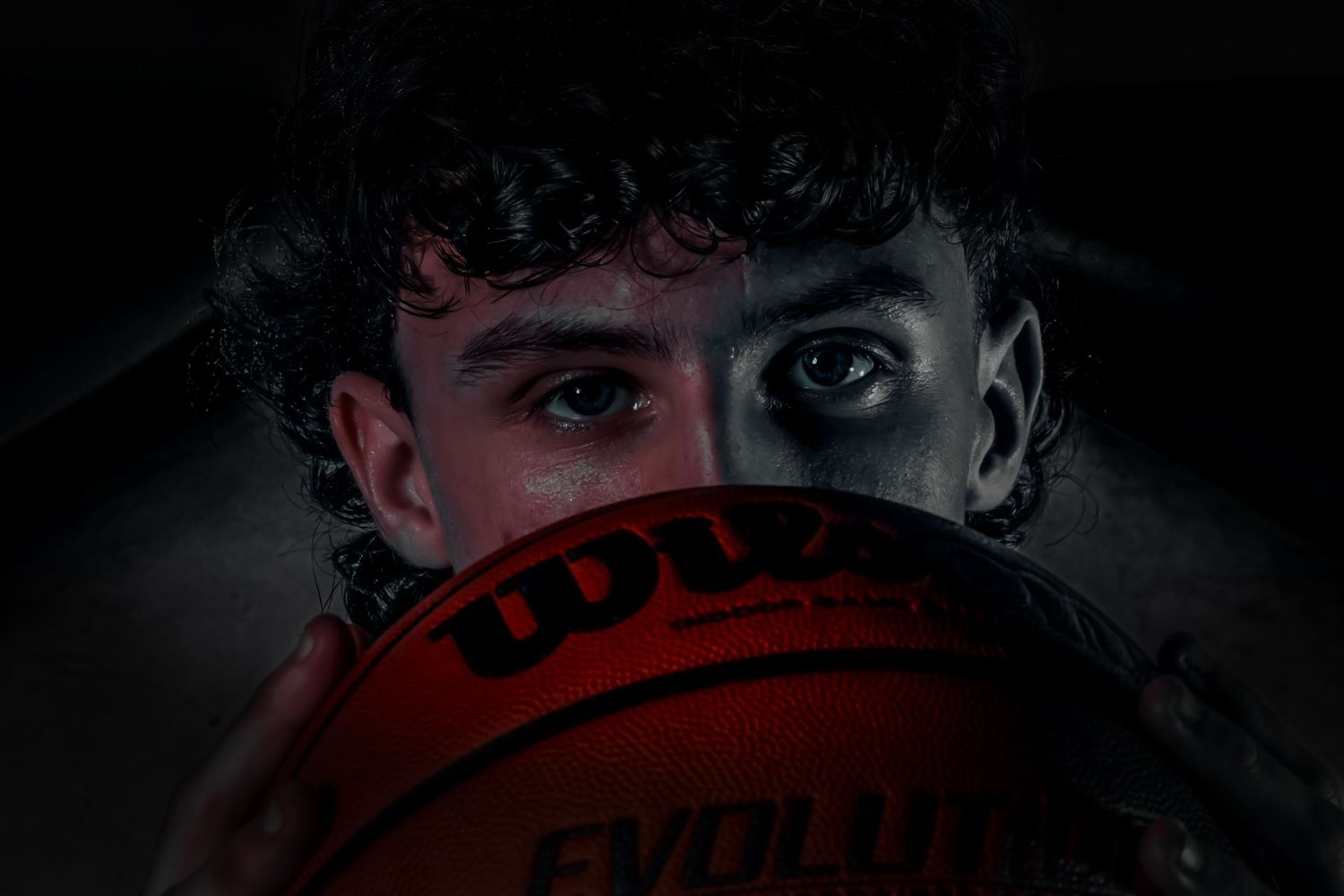 Close-up view of basketball with dramatic lighting creating dark shadows and texture.