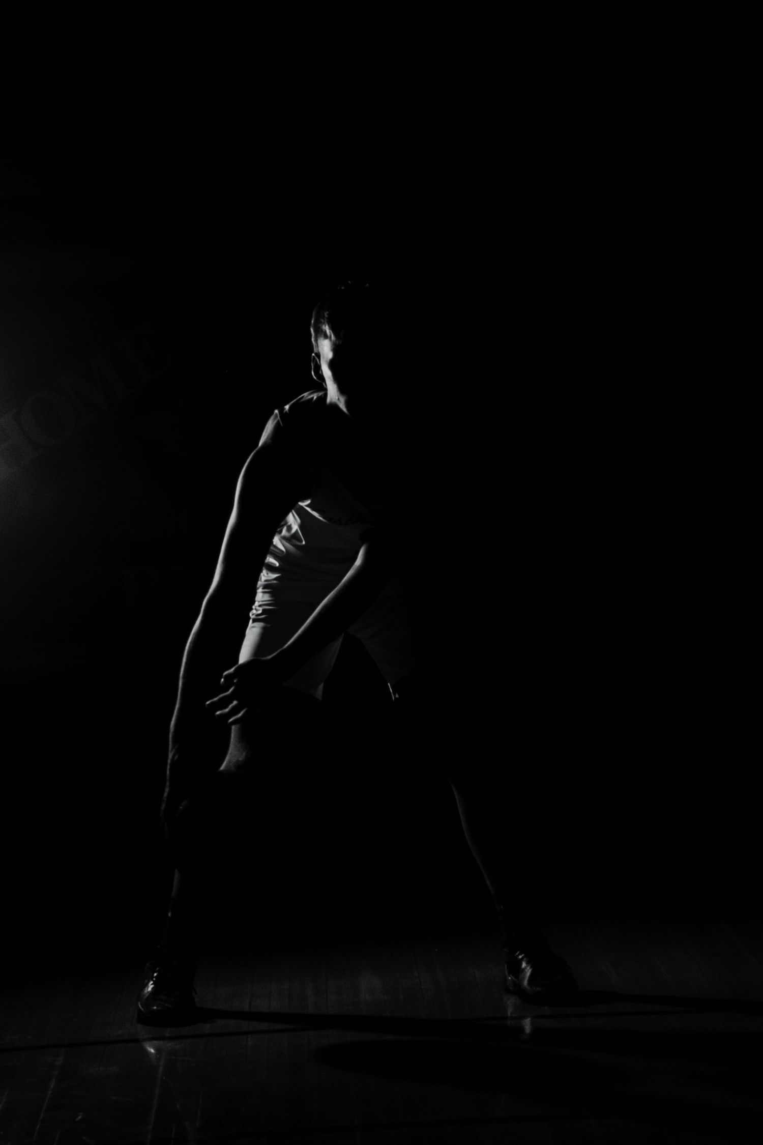 Silhouette of basketball player in dramatic pose against dark background.
