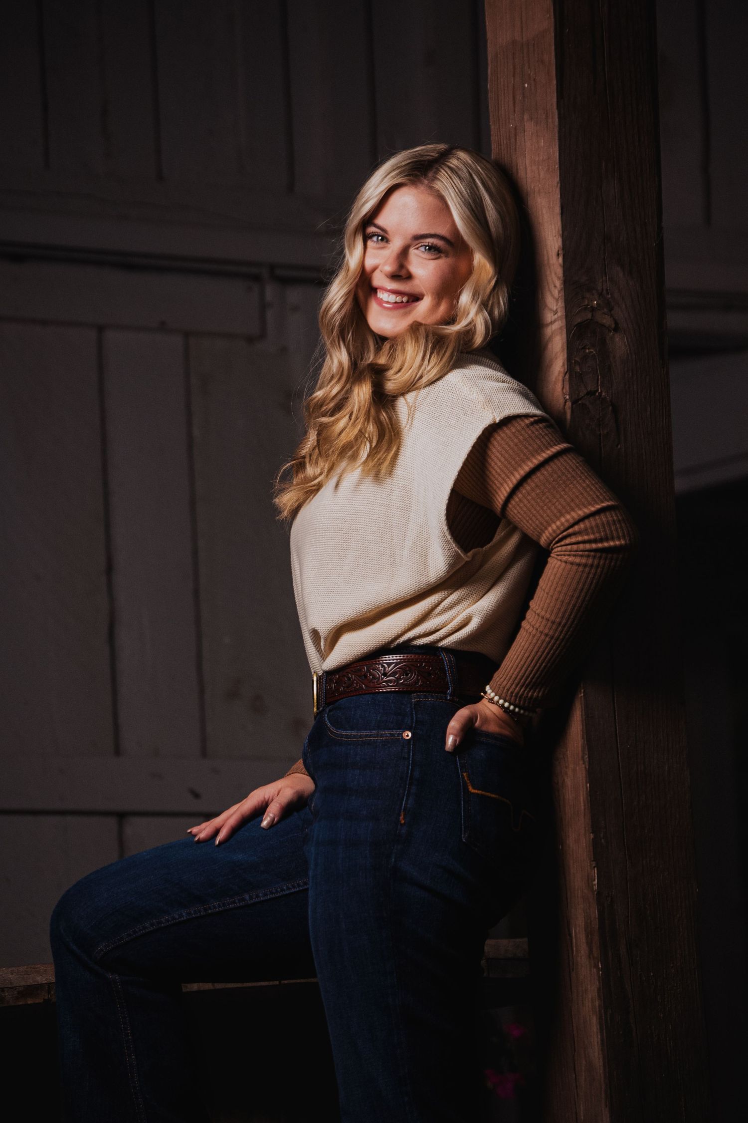 Stylish portrait against wooden beams wearing denim and a two-tone sweater.
