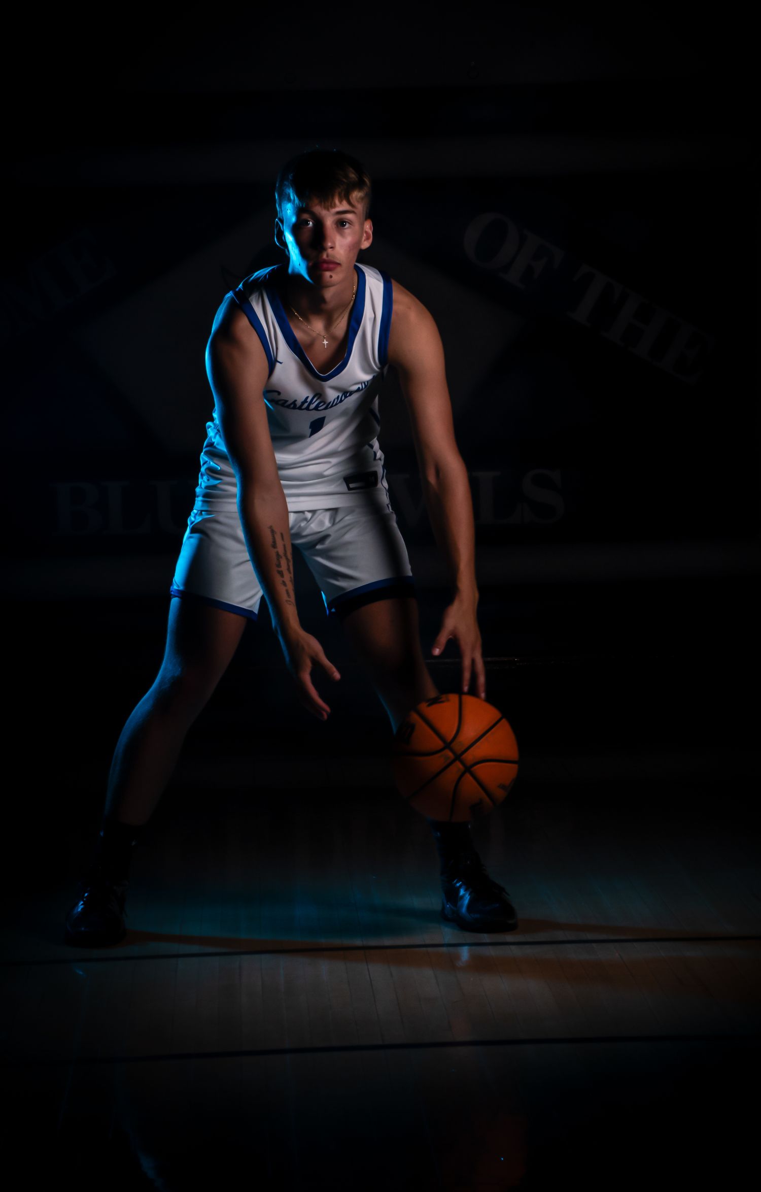 Low angle view of basketball player dribbling on court in dramatic lighting.