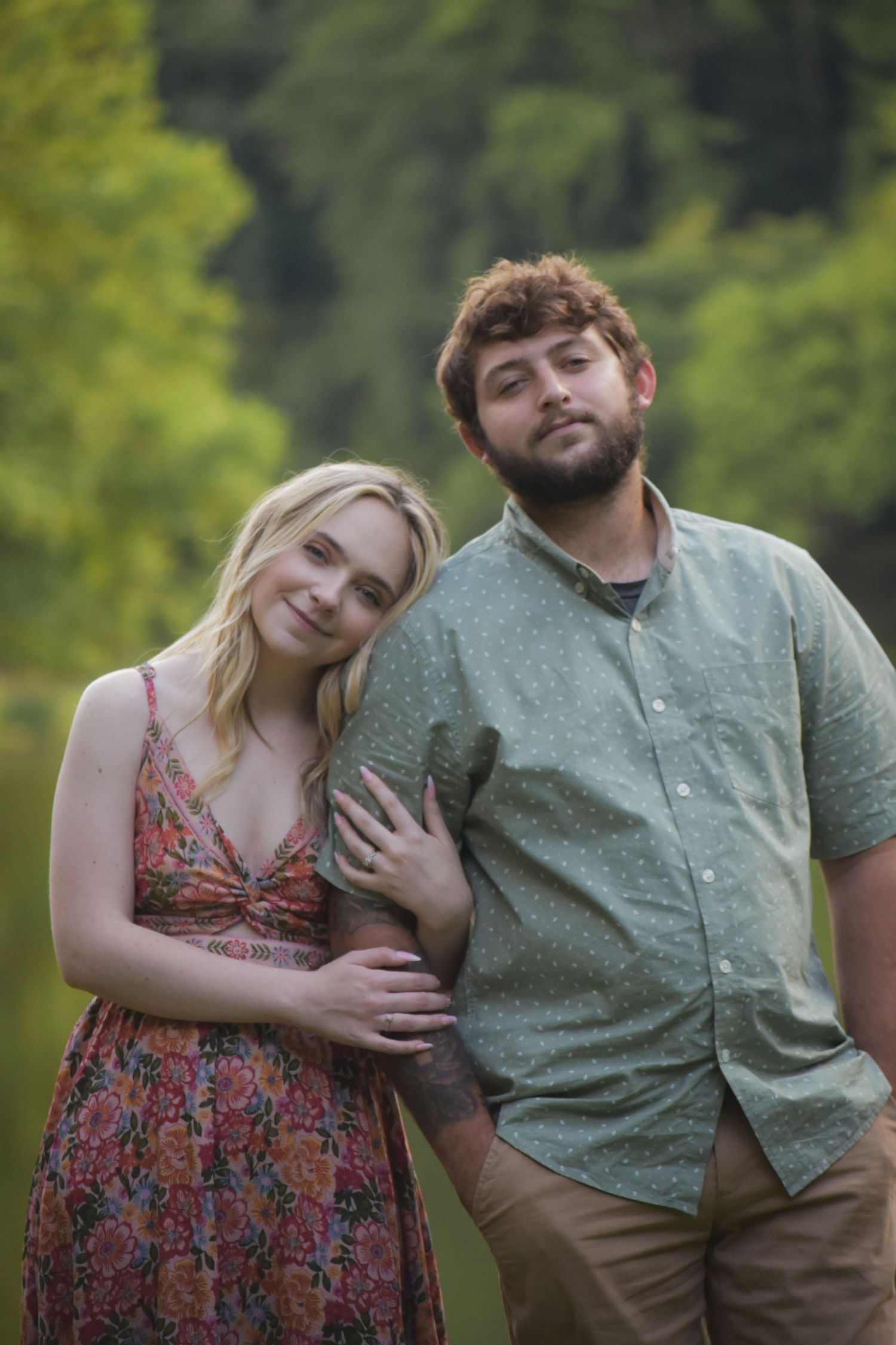 A playful couple poses together in a natural outdoor setting with greenery.