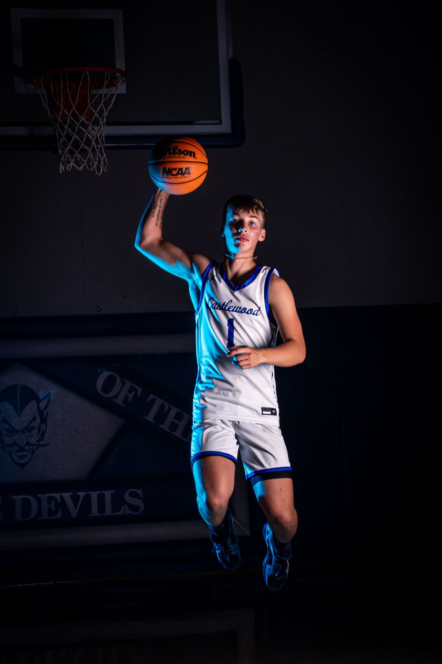 Player jumps with basketball in dramatic pose with blue lighting and smoke effects.