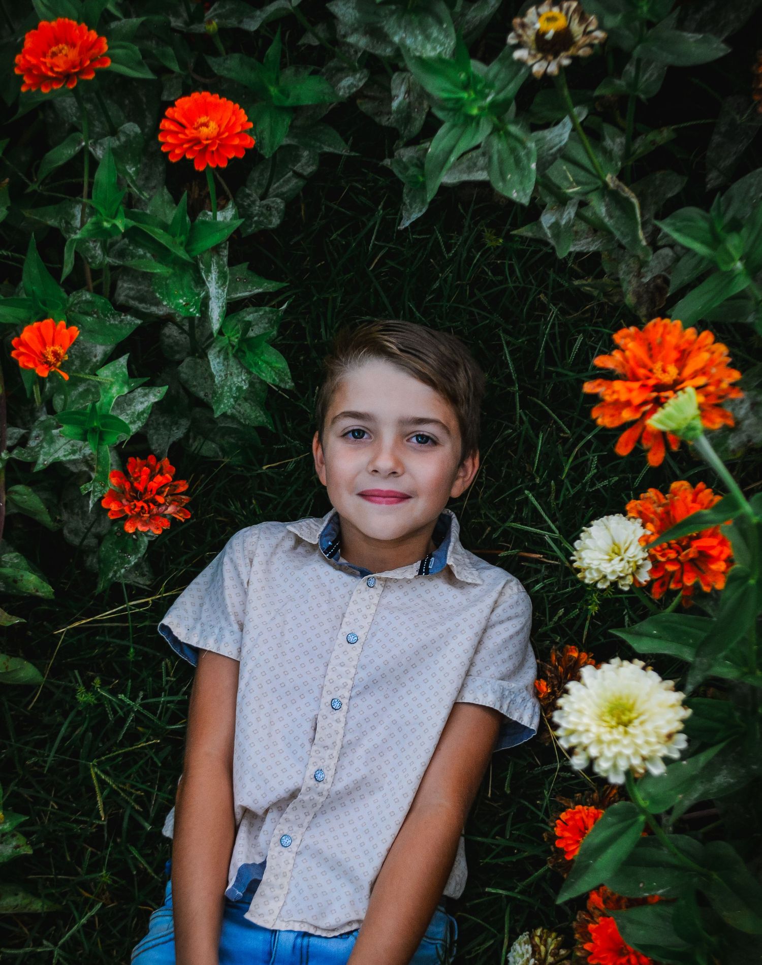 Orange and white zinnias bloom around a garden portrait setting.