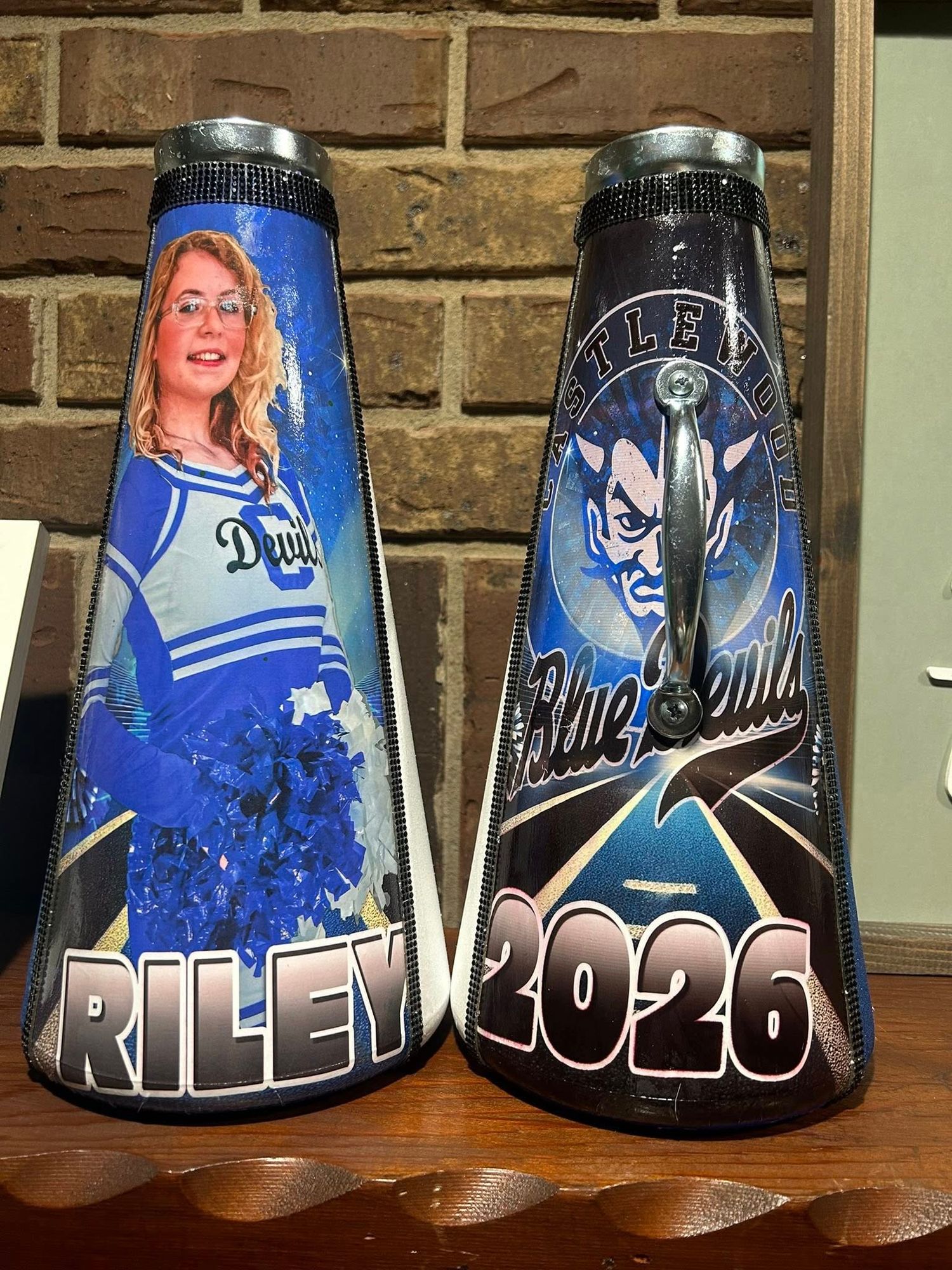 Custom painted megaphones with blue and black designs displayed against brick wall.
