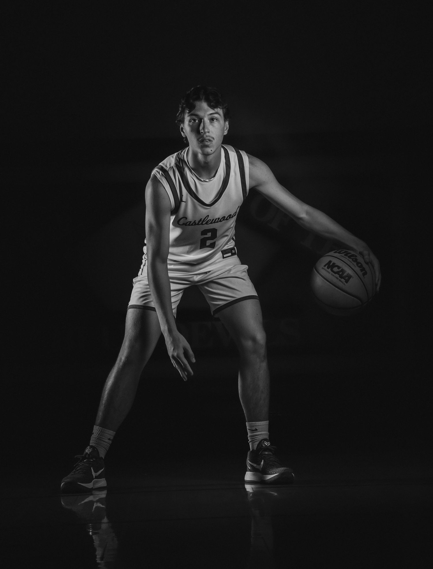 Black and white portrait of basketball player in defensive position.