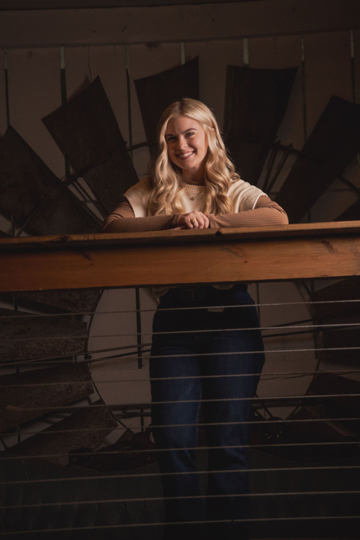 Casual portrait on wooden balcony with vintage fan backdrop in moody lighting.