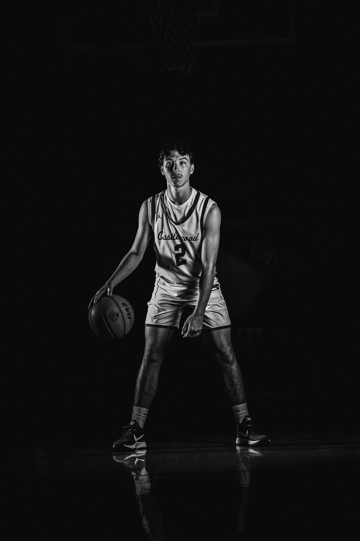 Black and white sports portrait of basketball player in action pose.