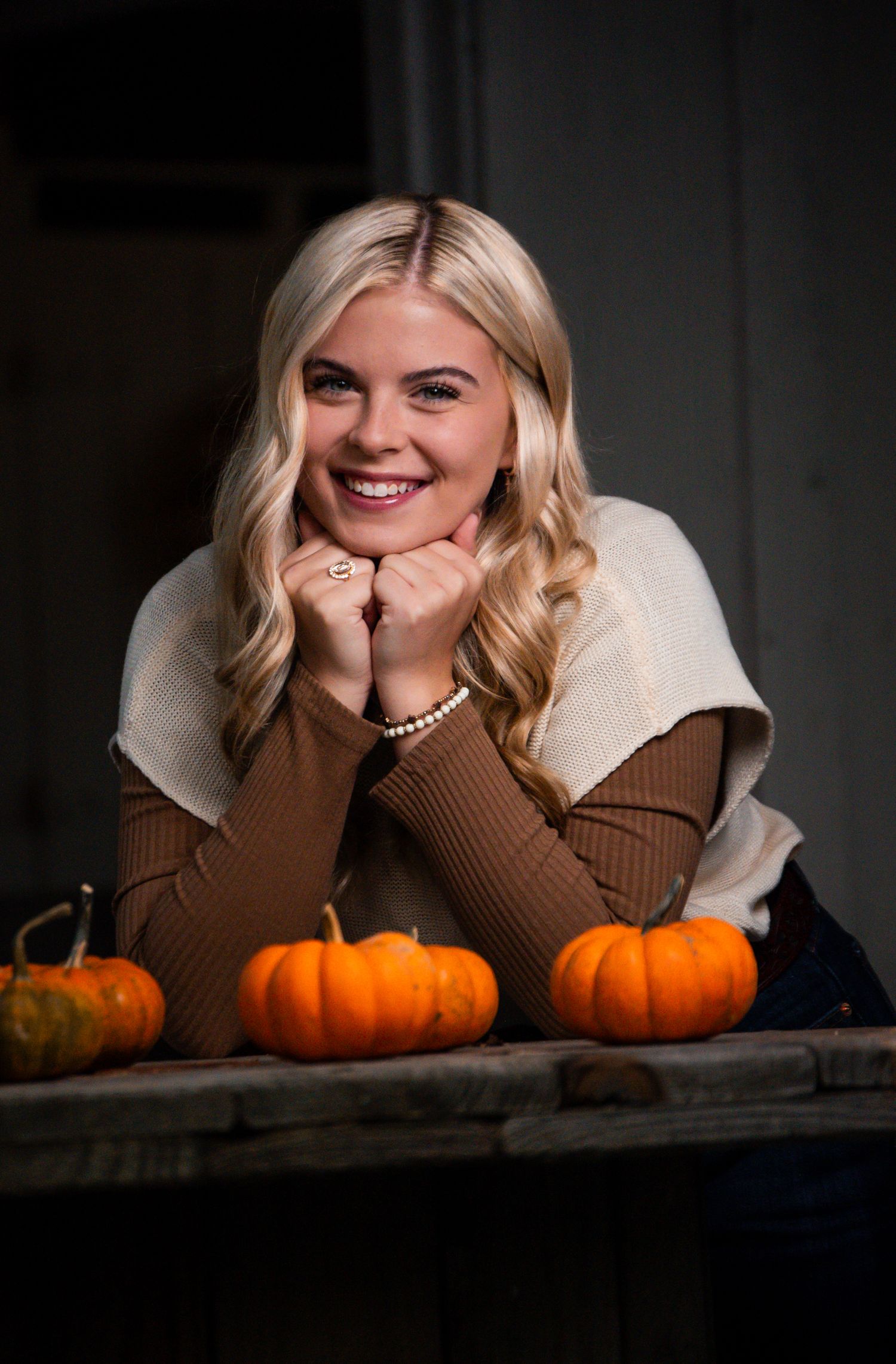 Cozy fall portrait with pumpkins and a brown and cream colored sweater.