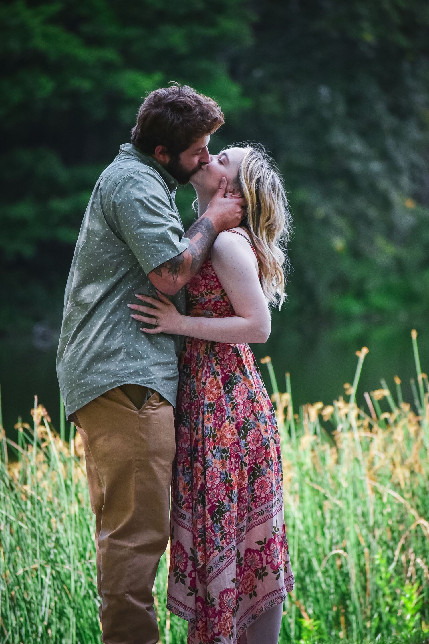 A couple shares a passionate moment surrounded by tall grass and wildflowers.