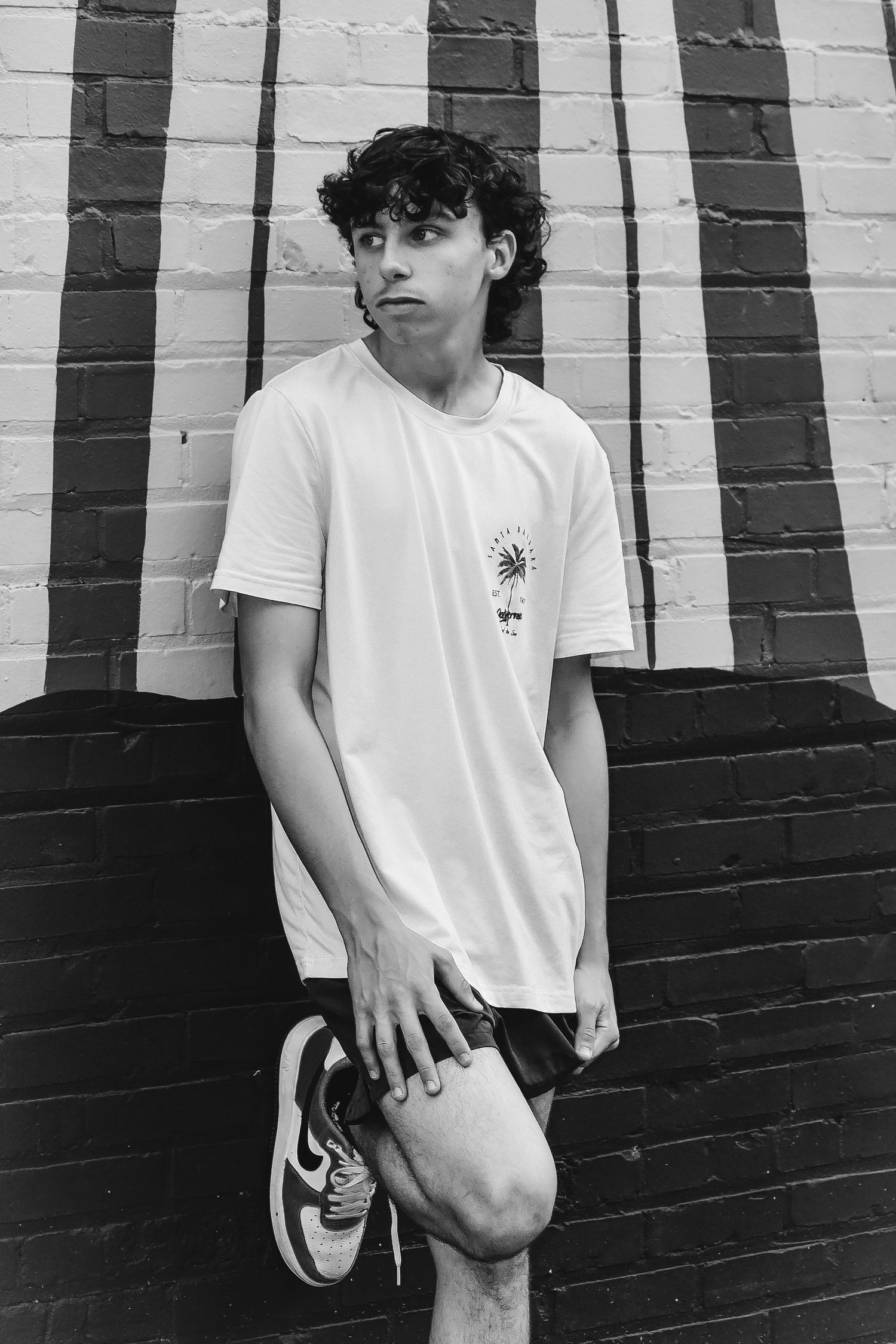 Black and white portrait against geometric painted wall wearing white t-shirt.
