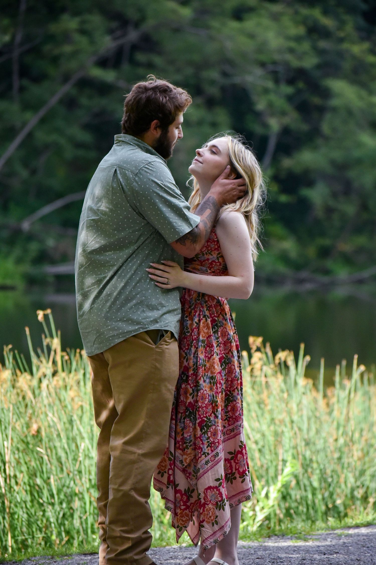 A romantic couple embraces in a field of tall grass during a tender outdoor photoshoot.