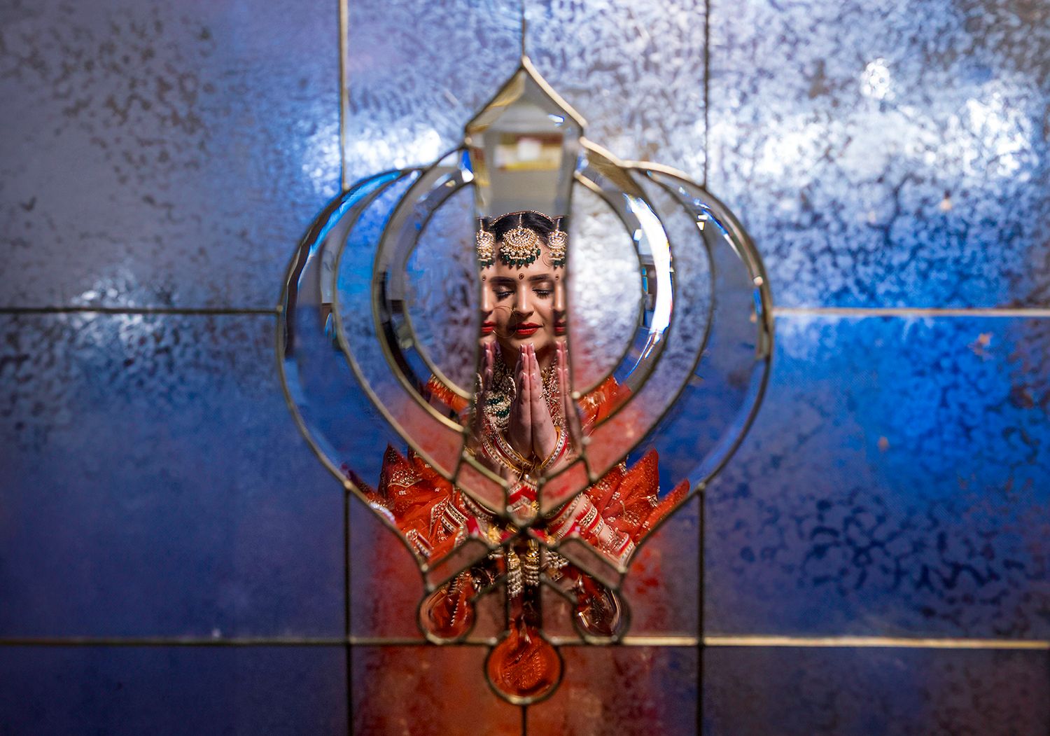 Artistic blue and red wedding portrait composition with decorative framing elements.