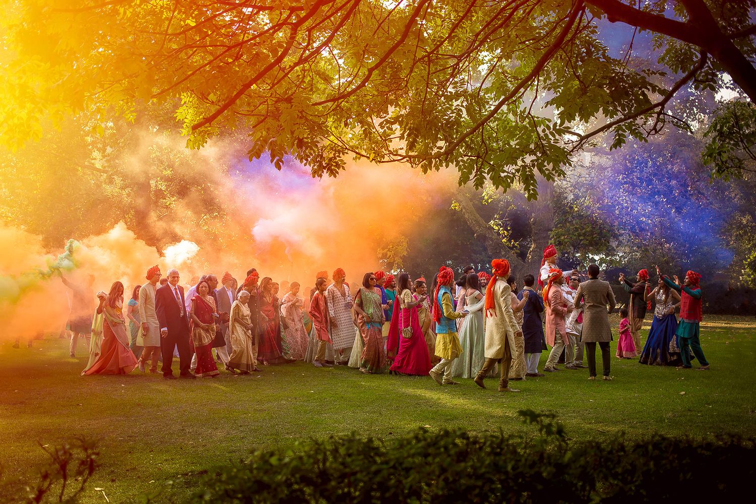 Panoramic wedding party group shot with warm sunset lighting and natural landscape.