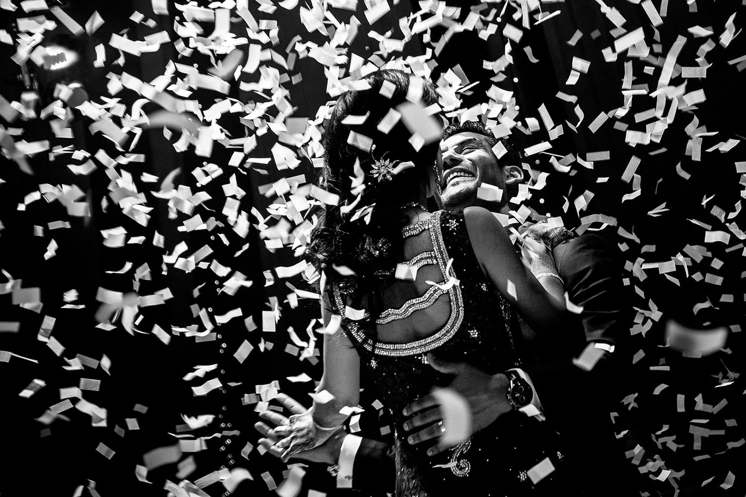 White confetti falls from above during a celebration or event against a dark background.