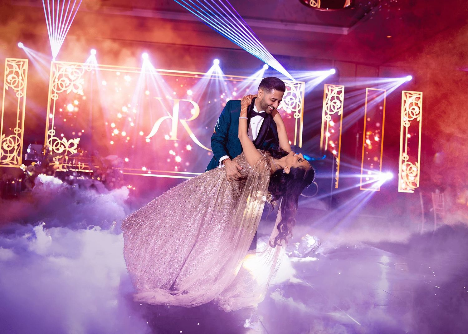 A dance floor illuminated with pink and purple lights creates a dreamy atmosphere at a wedding reception.