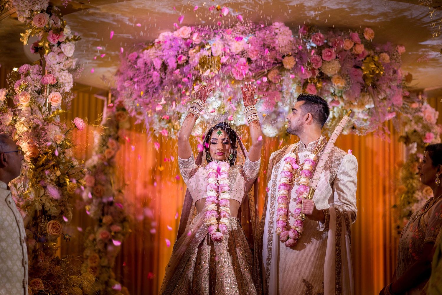 Elegant pink cherry blossoms and floral decorations create a romantic indoor wedding setting.