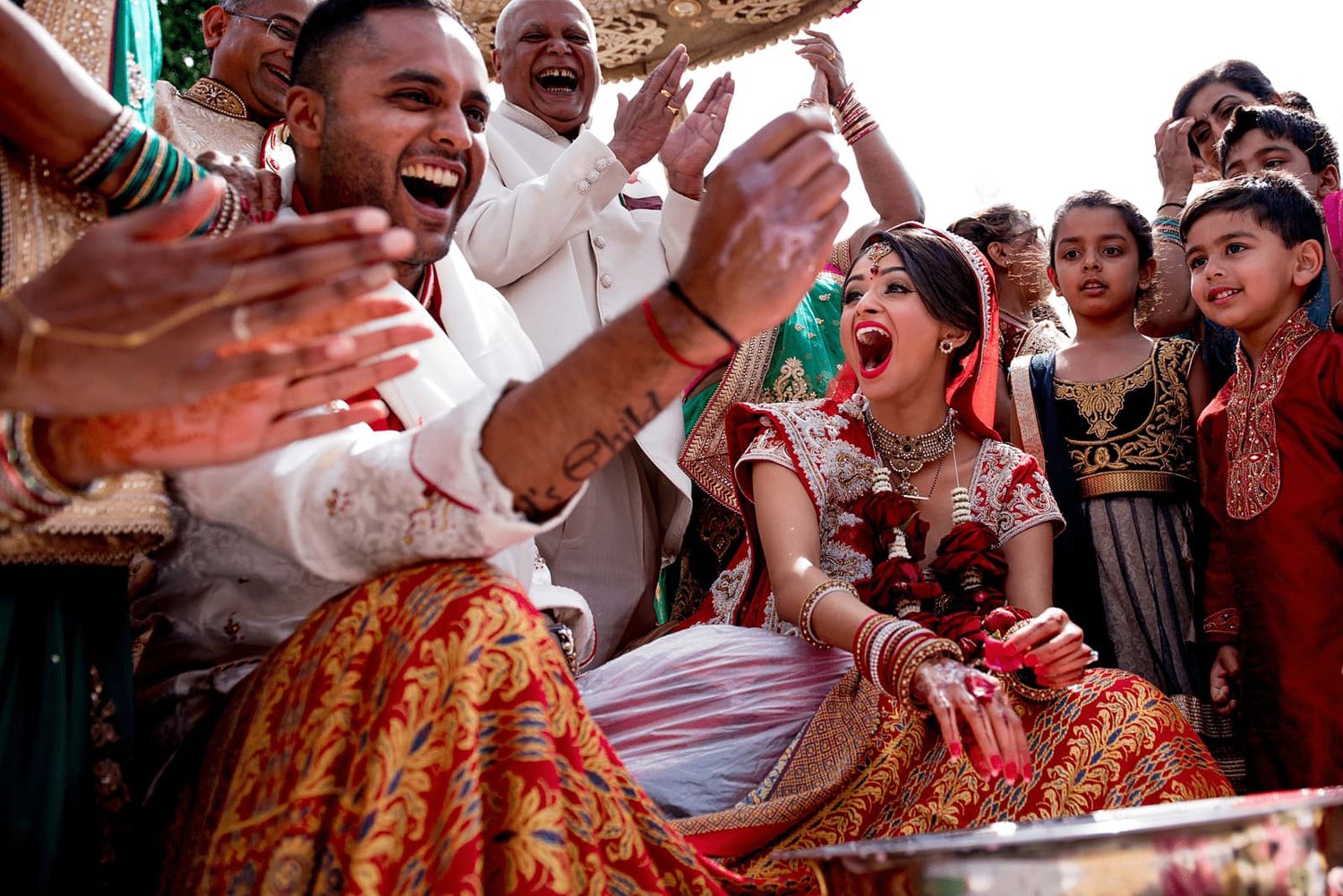 A joyous celebration at an Indian wedding with guests dancing and throwing colorful powder during the festivities.